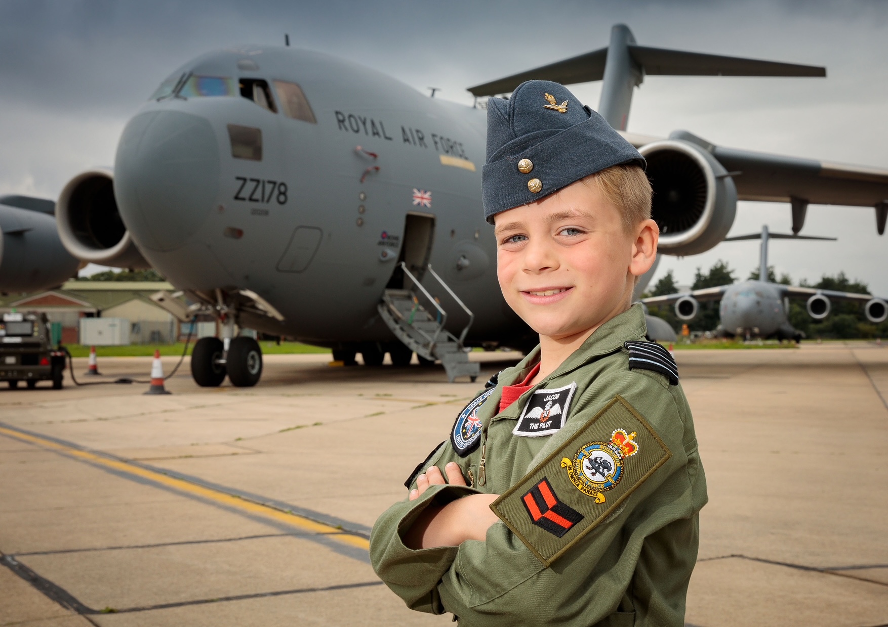 A boy wearing a pilot uniform in front of a plane