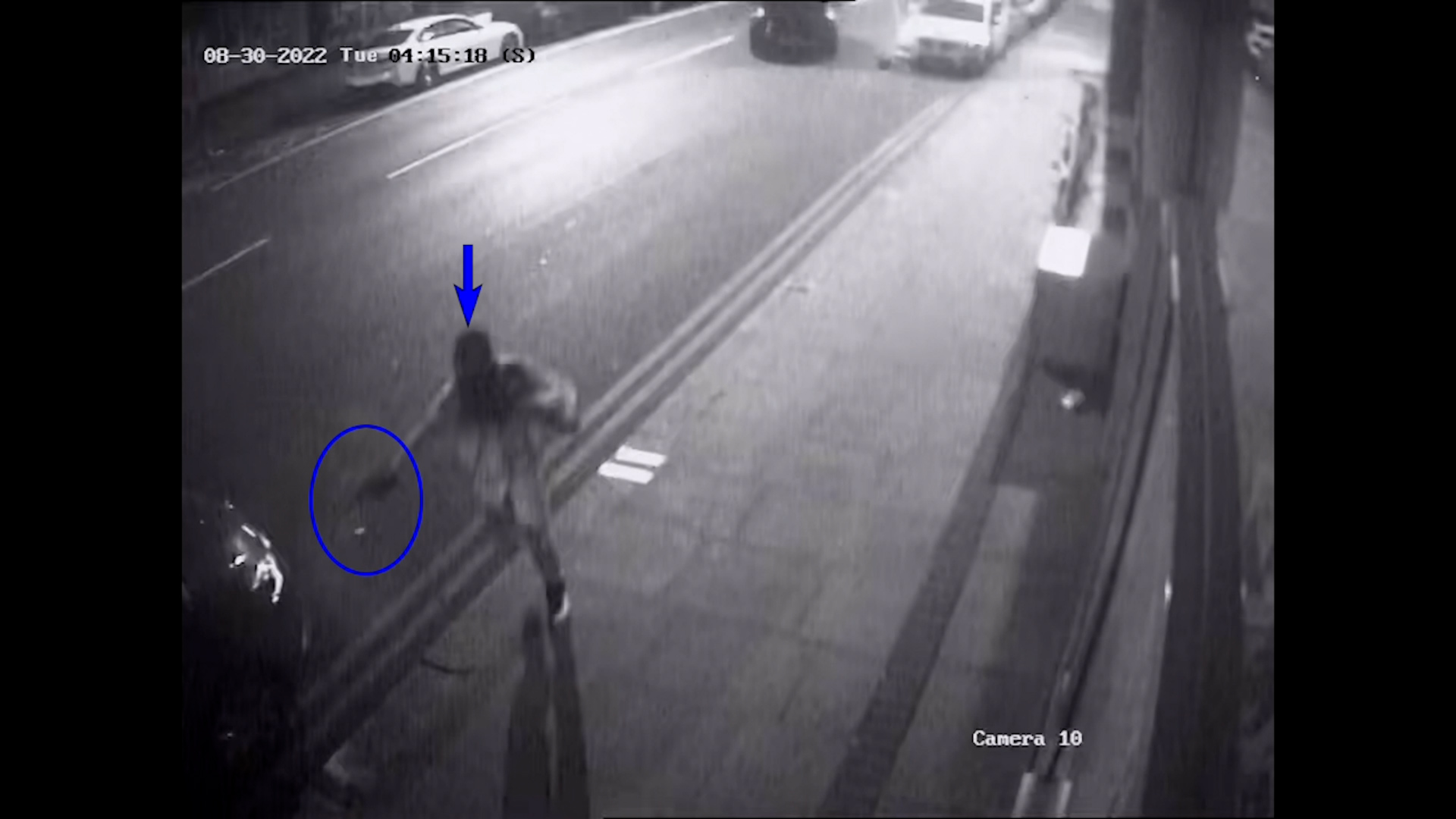 A CCTV still of a masked gunman holding a weapon in a firing position