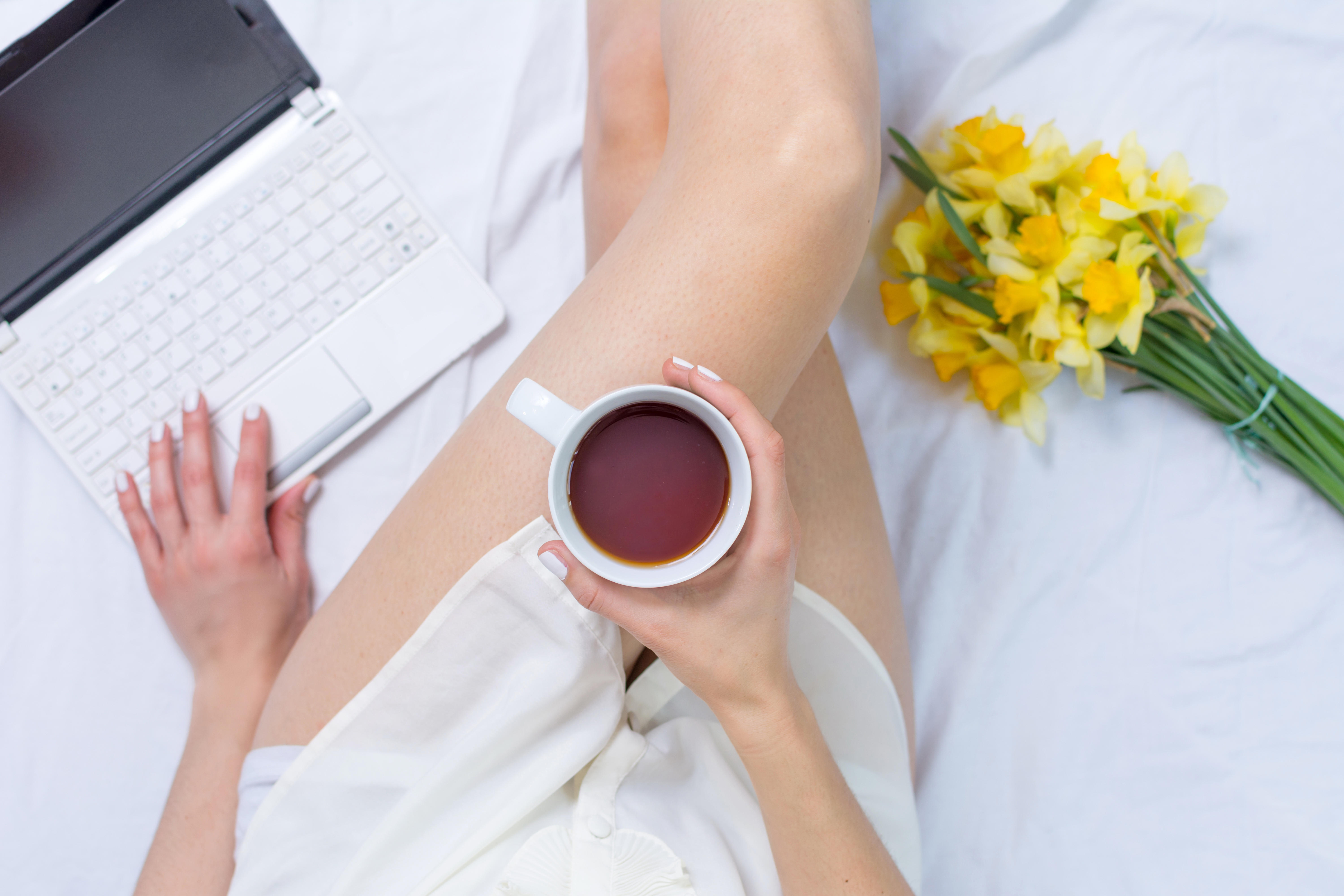 Woman having a morning cup of tea in bed