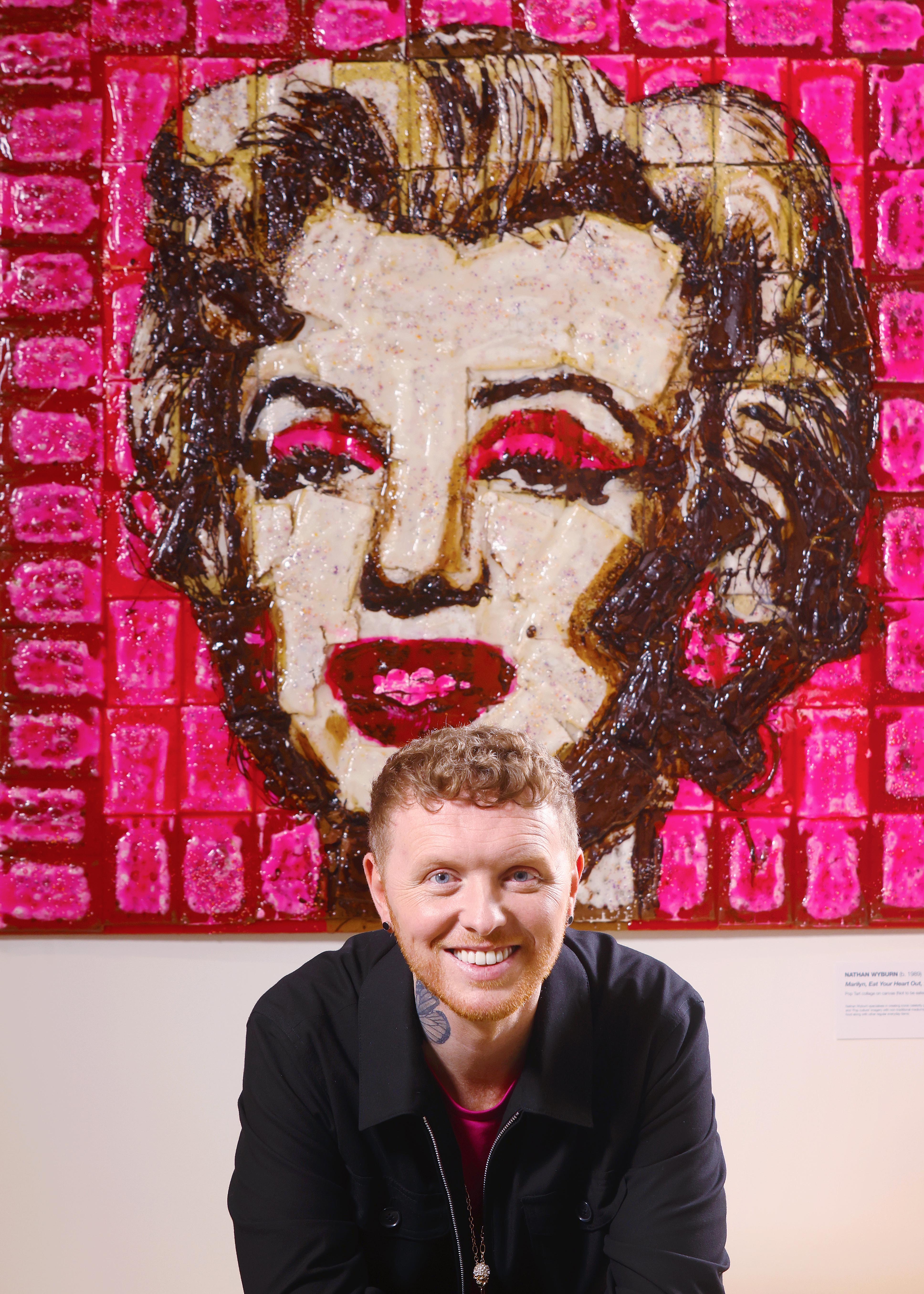 Image of a Marilyn Monroe portrait made from Pop Tarts with the artist sat in front of portrait