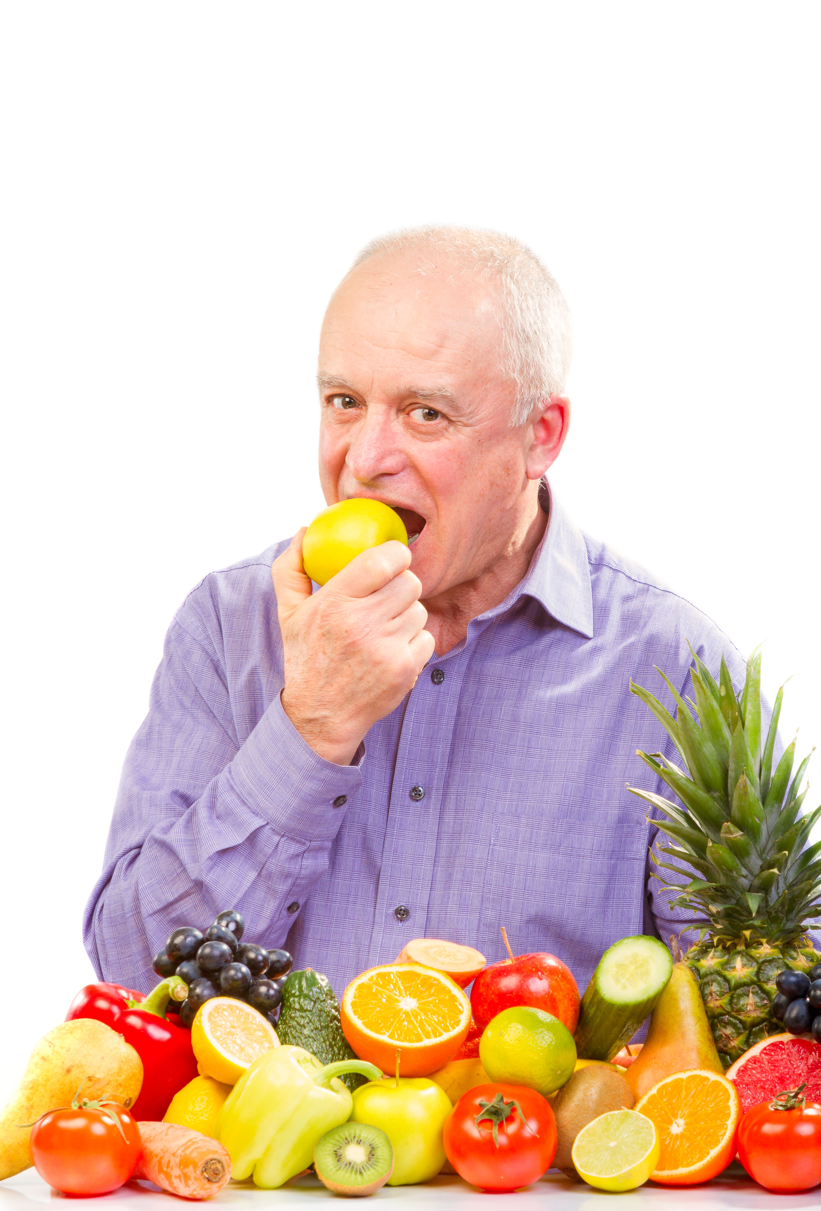 Closeup of senior man eating a green apple with a pile of fruit infront of him