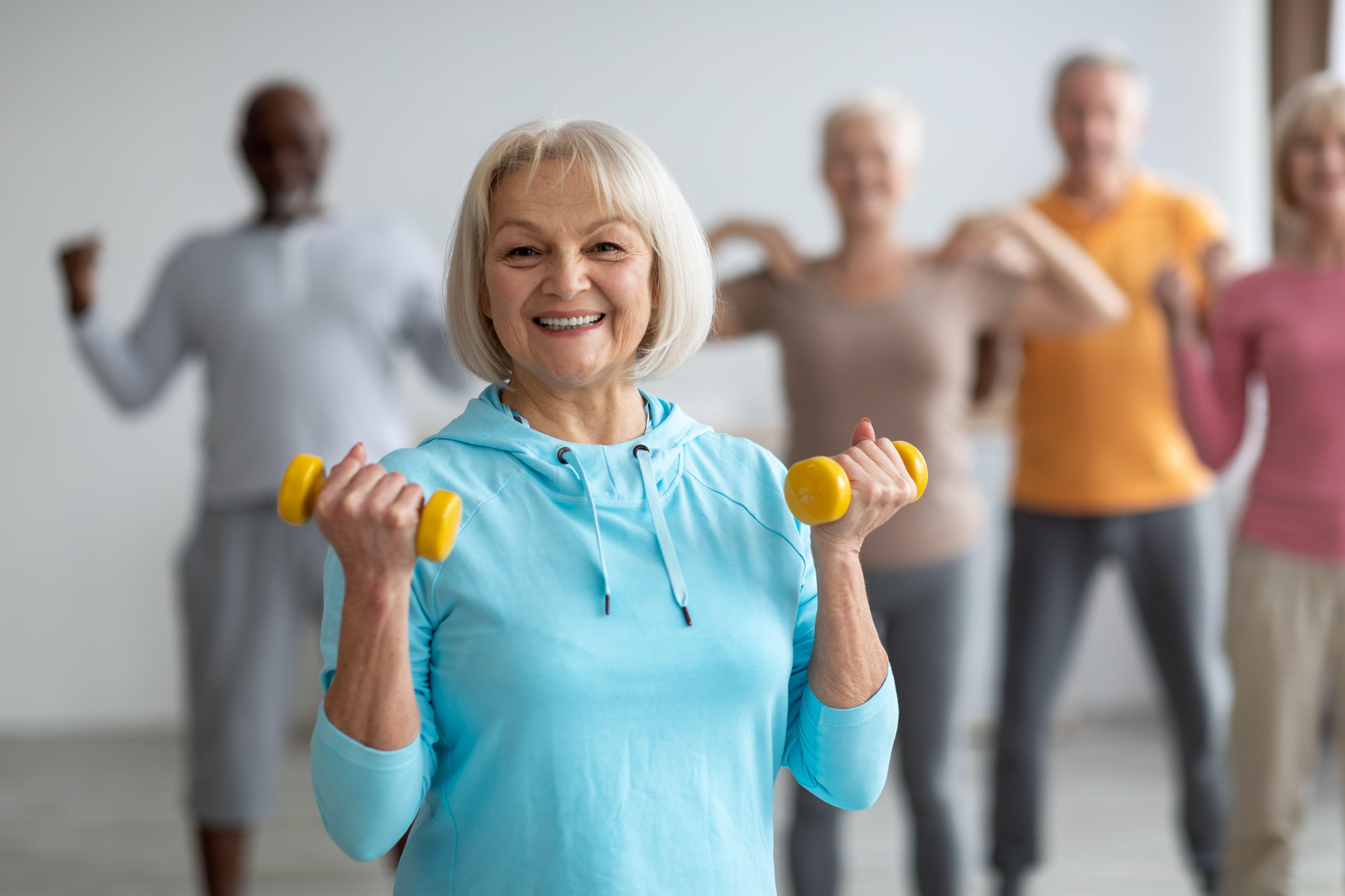 Smiley senior woman taking part in a weight training class 