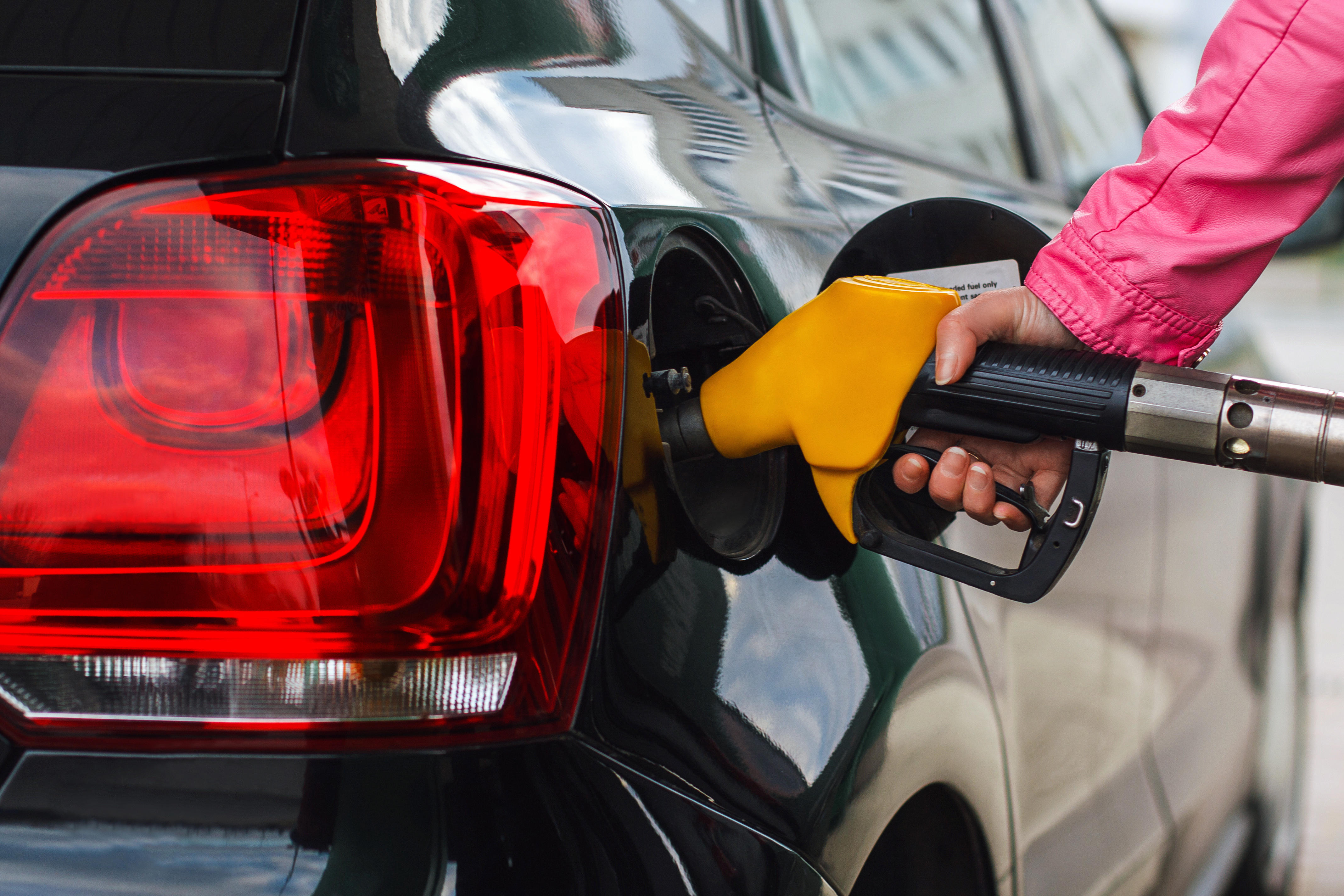 Woman filling up black car at petrol station 