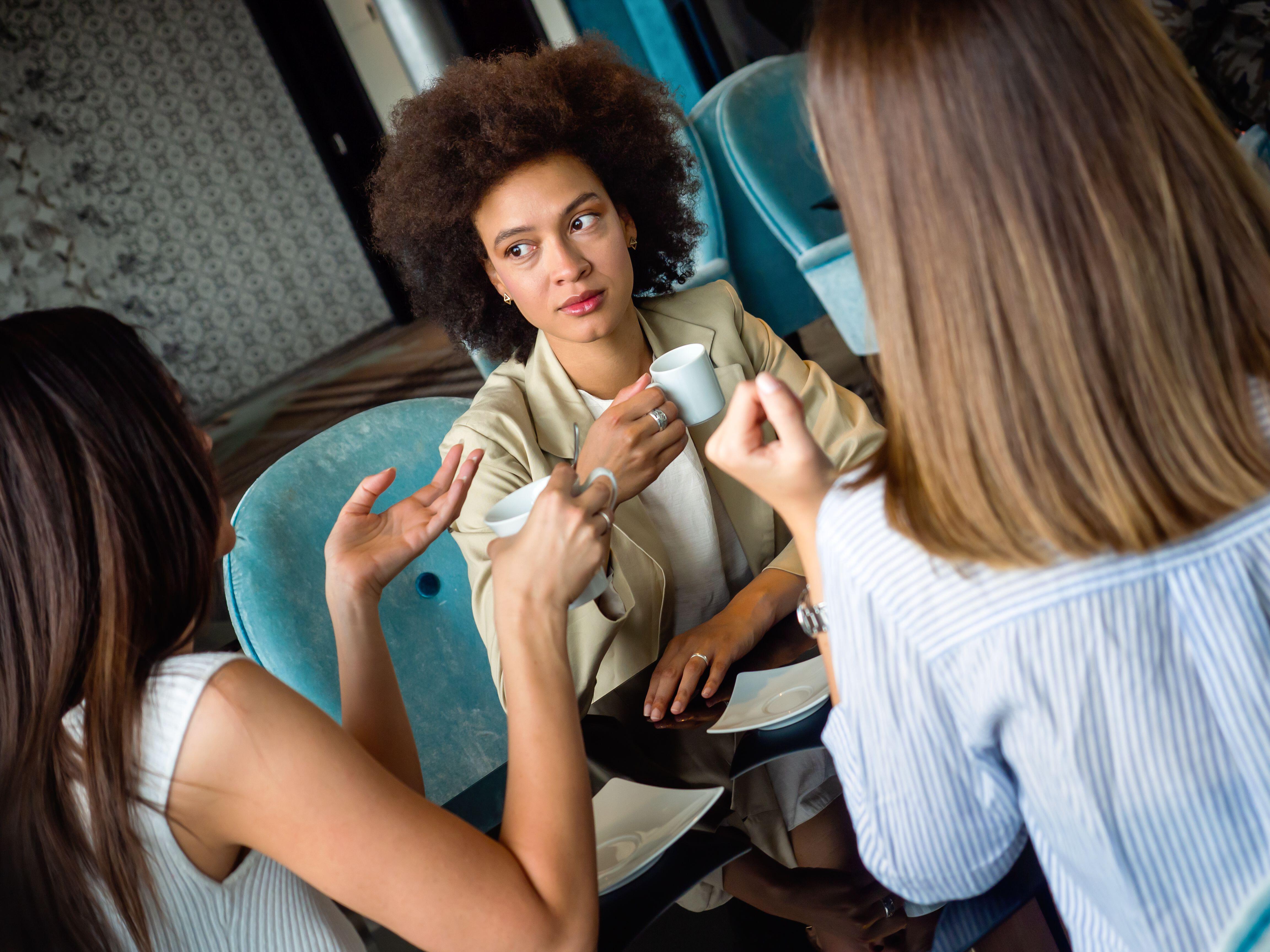 Three young women having a serious conversation at a cafe 