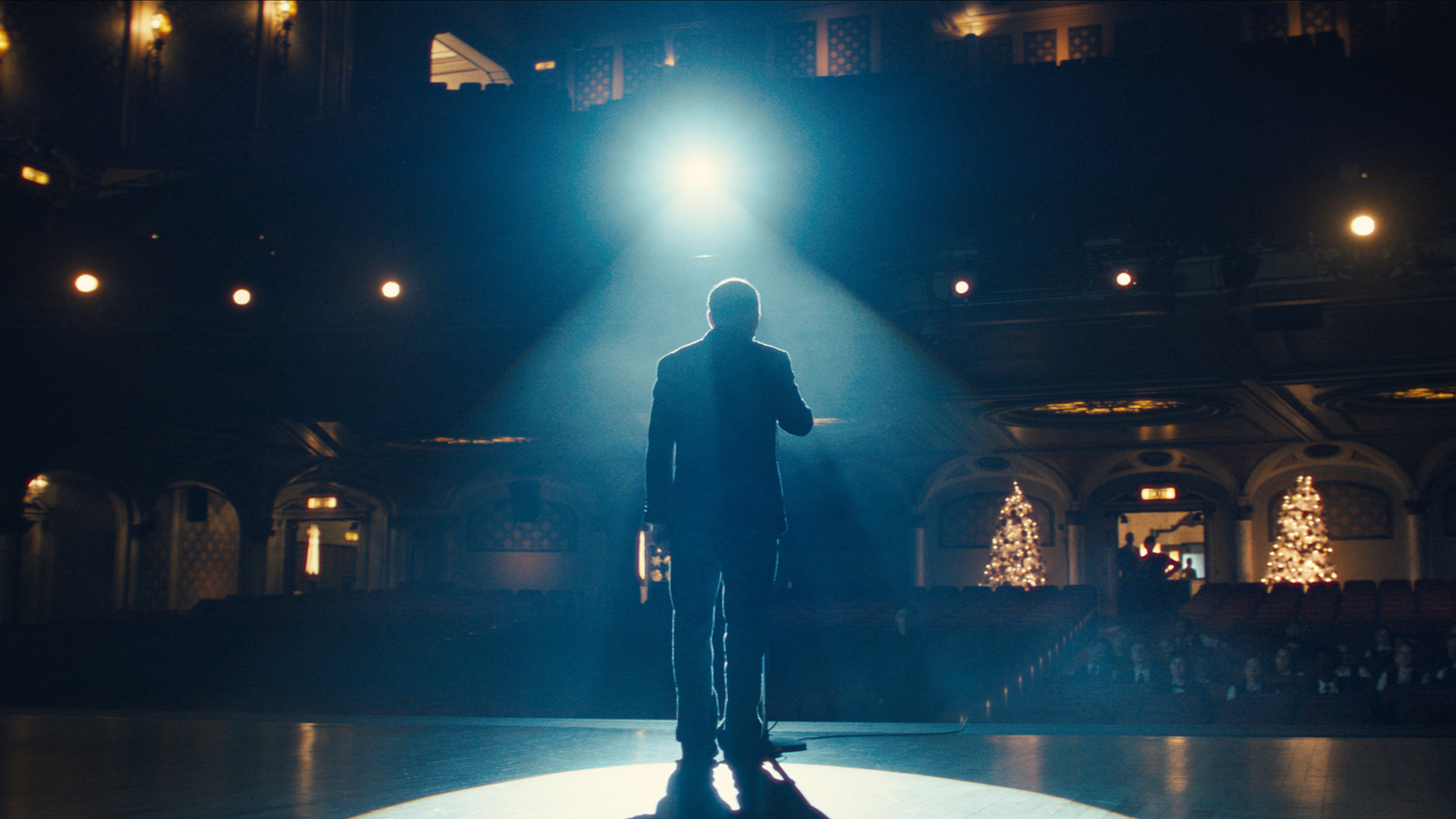 A still photo from this year's Amazon Christmas ad featuring a caretaker standing on a stage in the spotlight