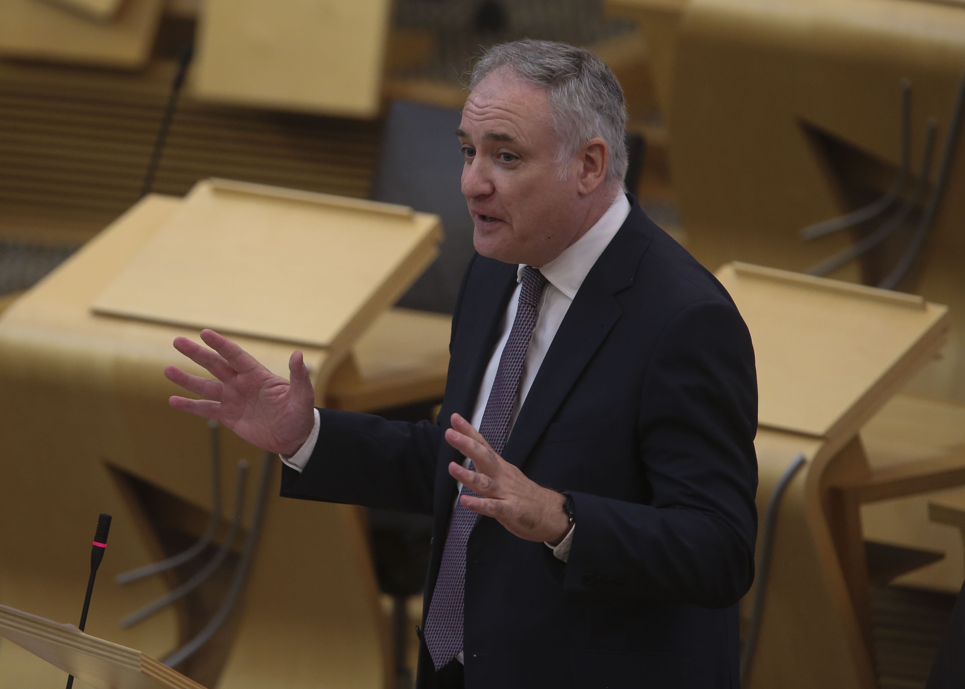 Richard Lochhead standing while speaking in Parliament