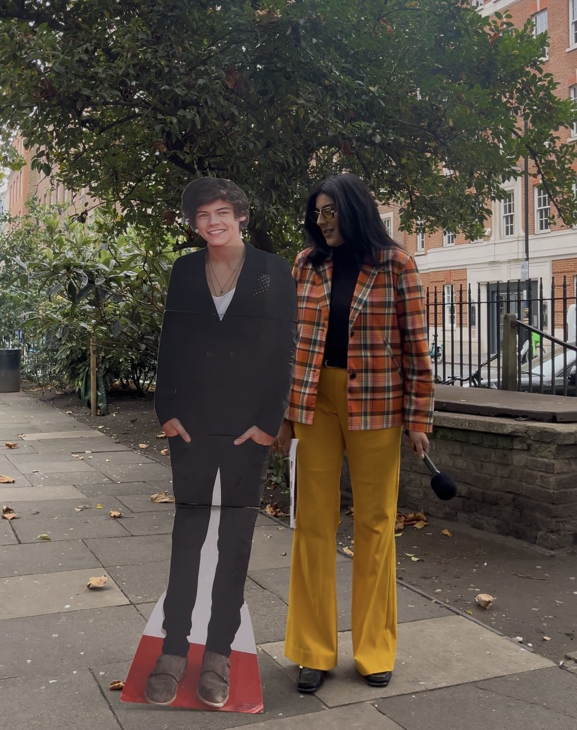 A woman standing beside a cut out of Harry Styles