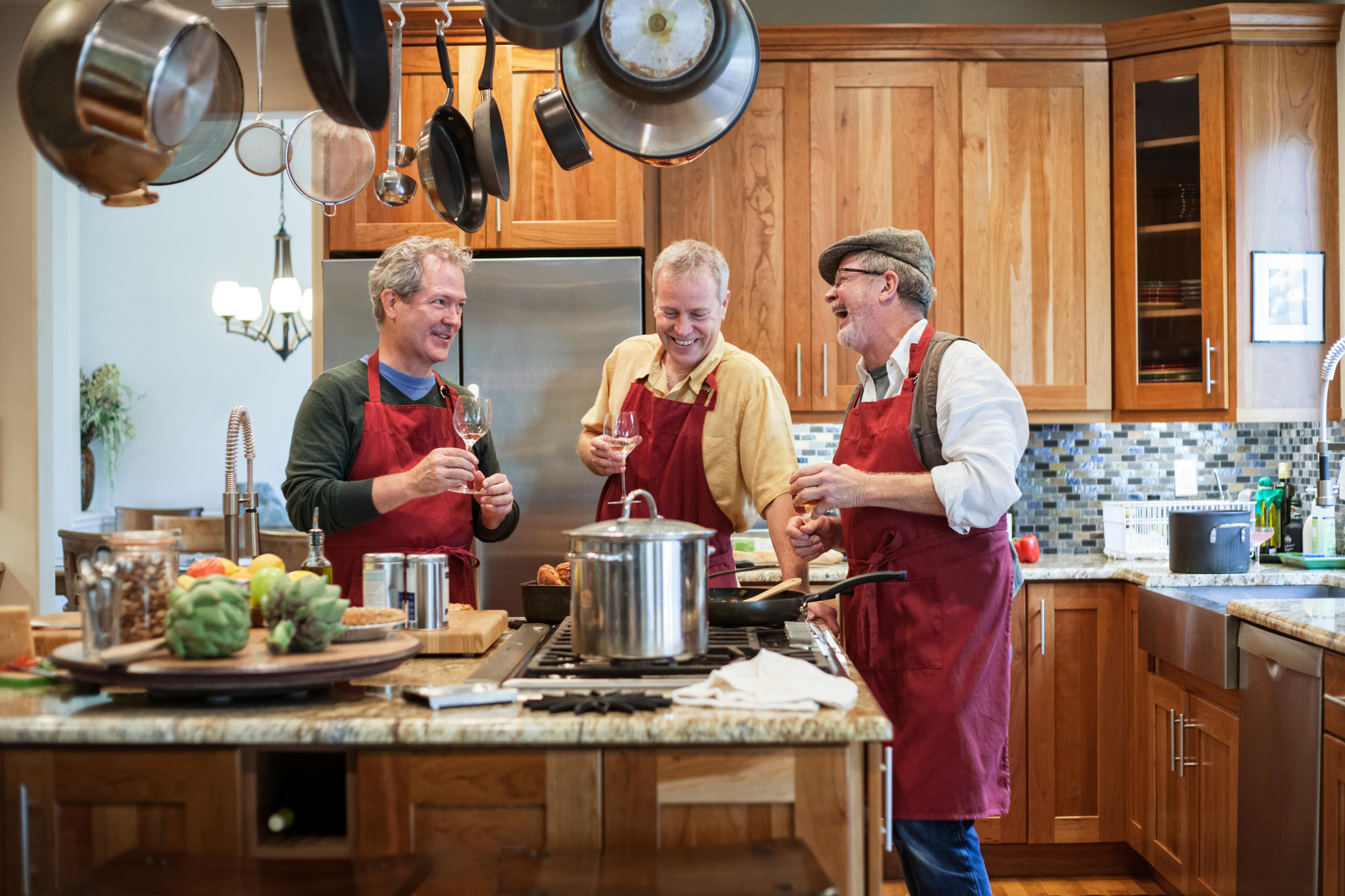 Three senior men friends cooking a meal in the kitchen.