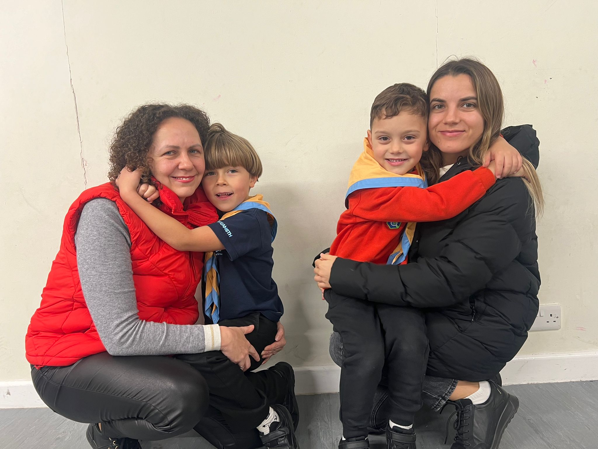 Two young boys hugging their mothers