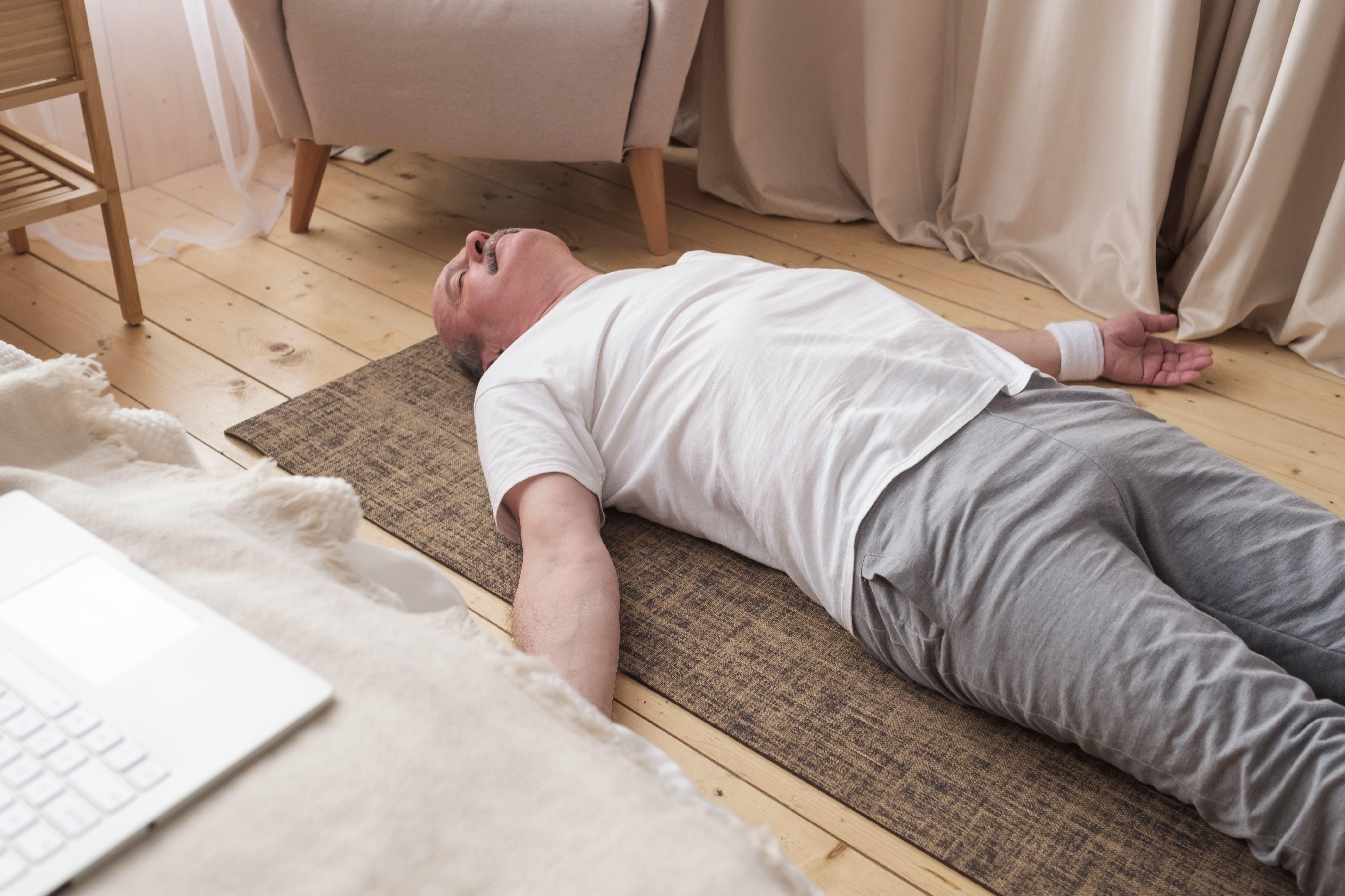 Old man laying on a yoga mat on the floor