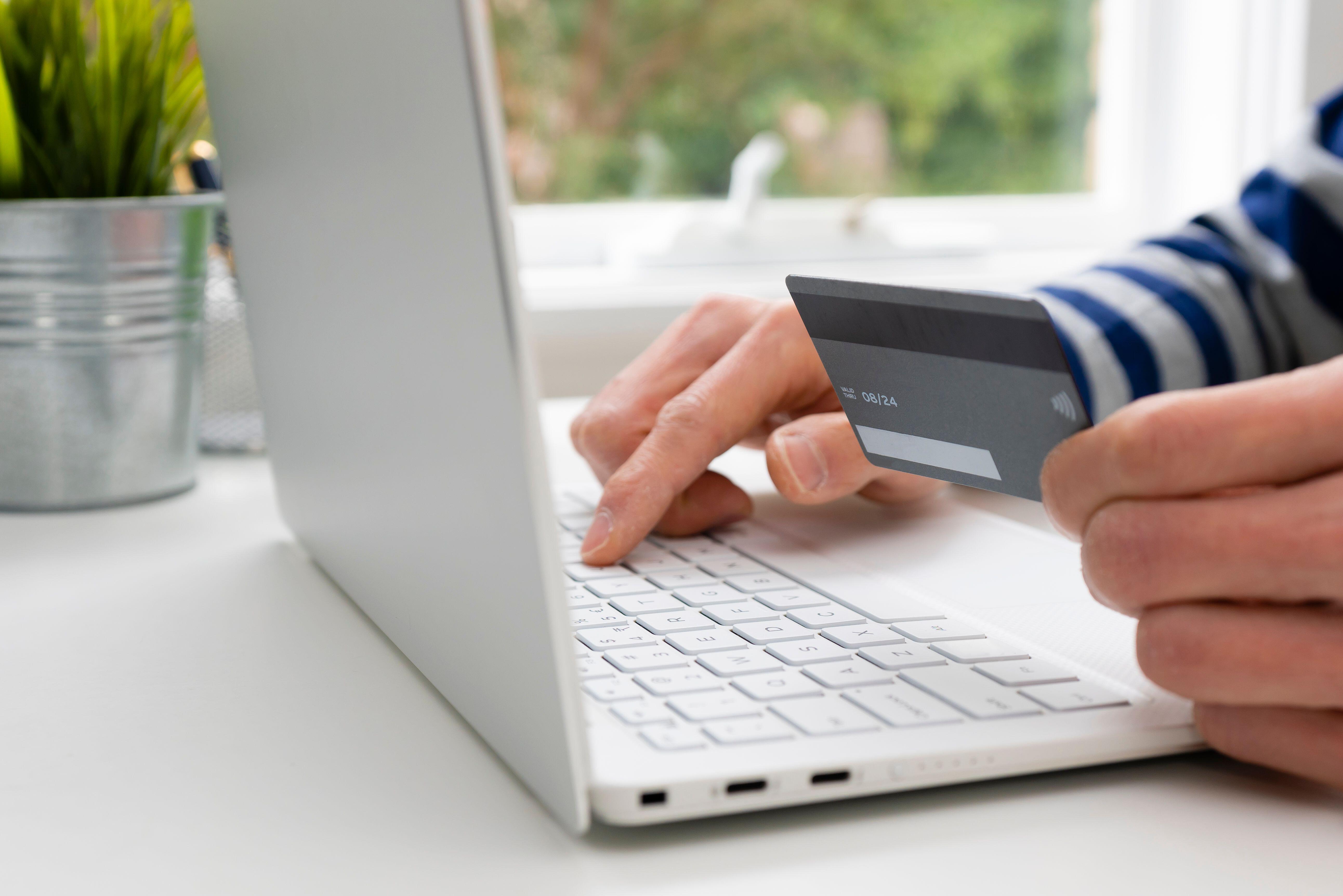 A number holding a bank card while using a laptop