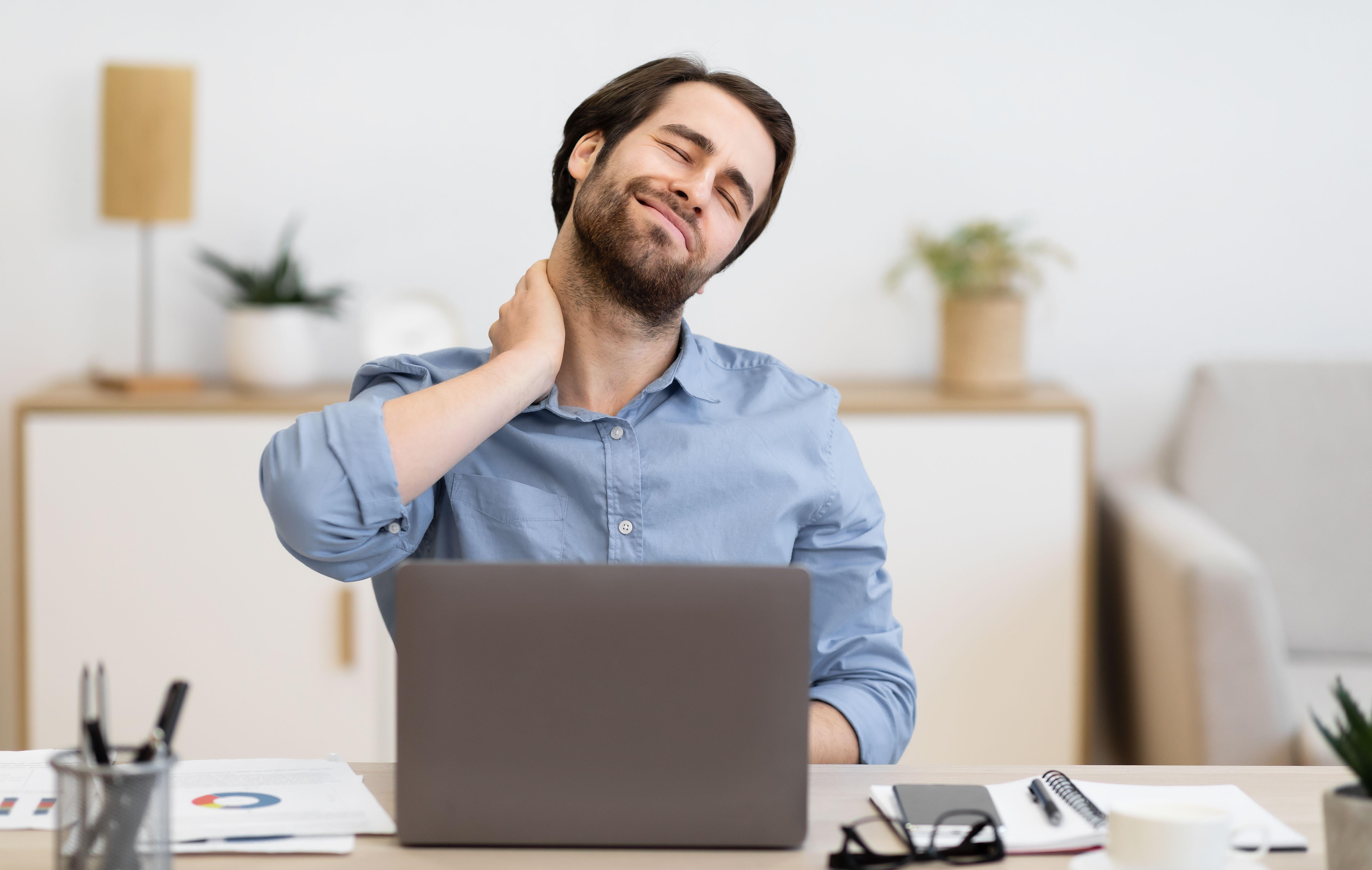 Tired businessman sat at her desk experiencing neck stiffness