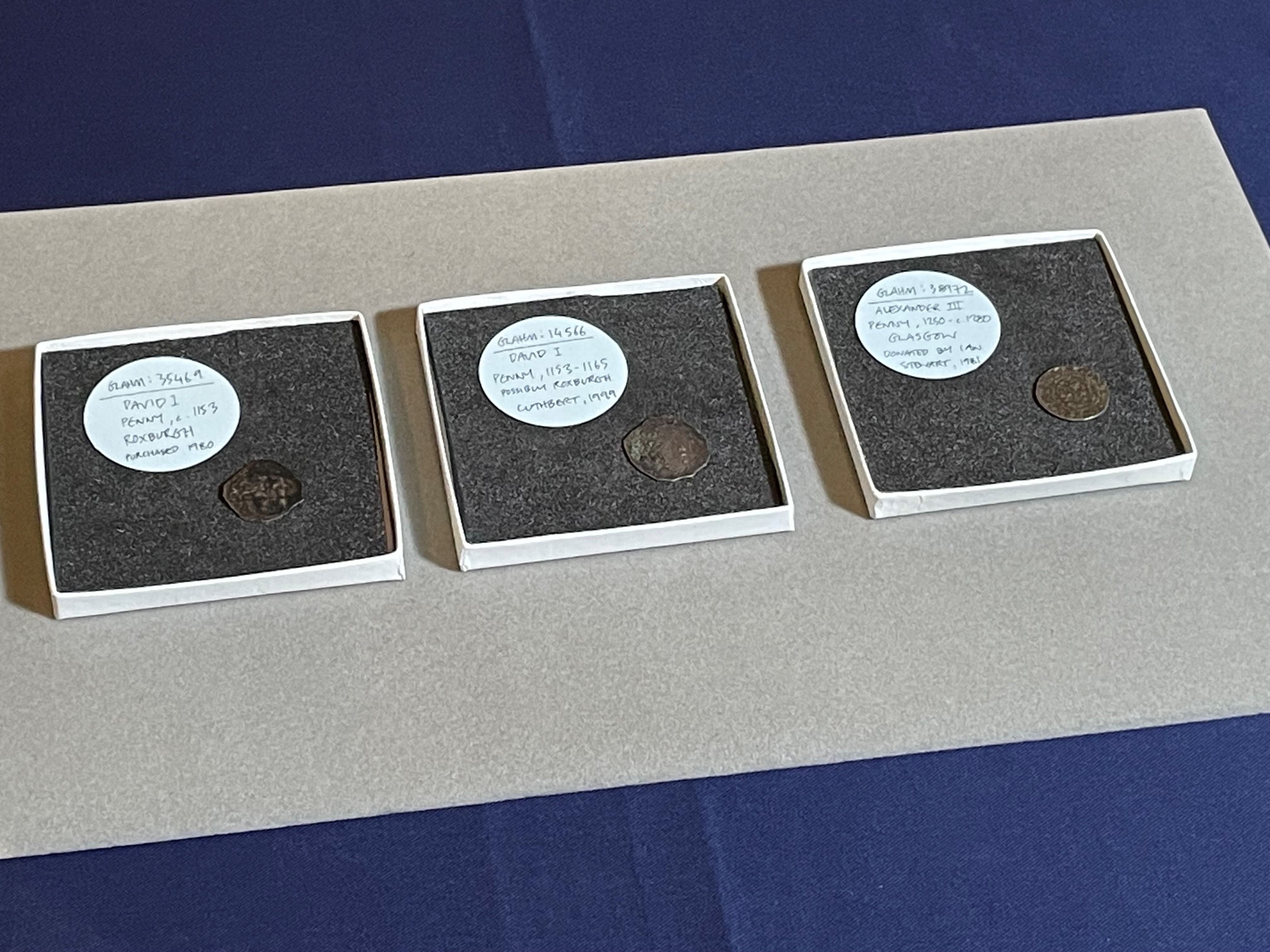 Three coins sitting in separate square boxes on a table