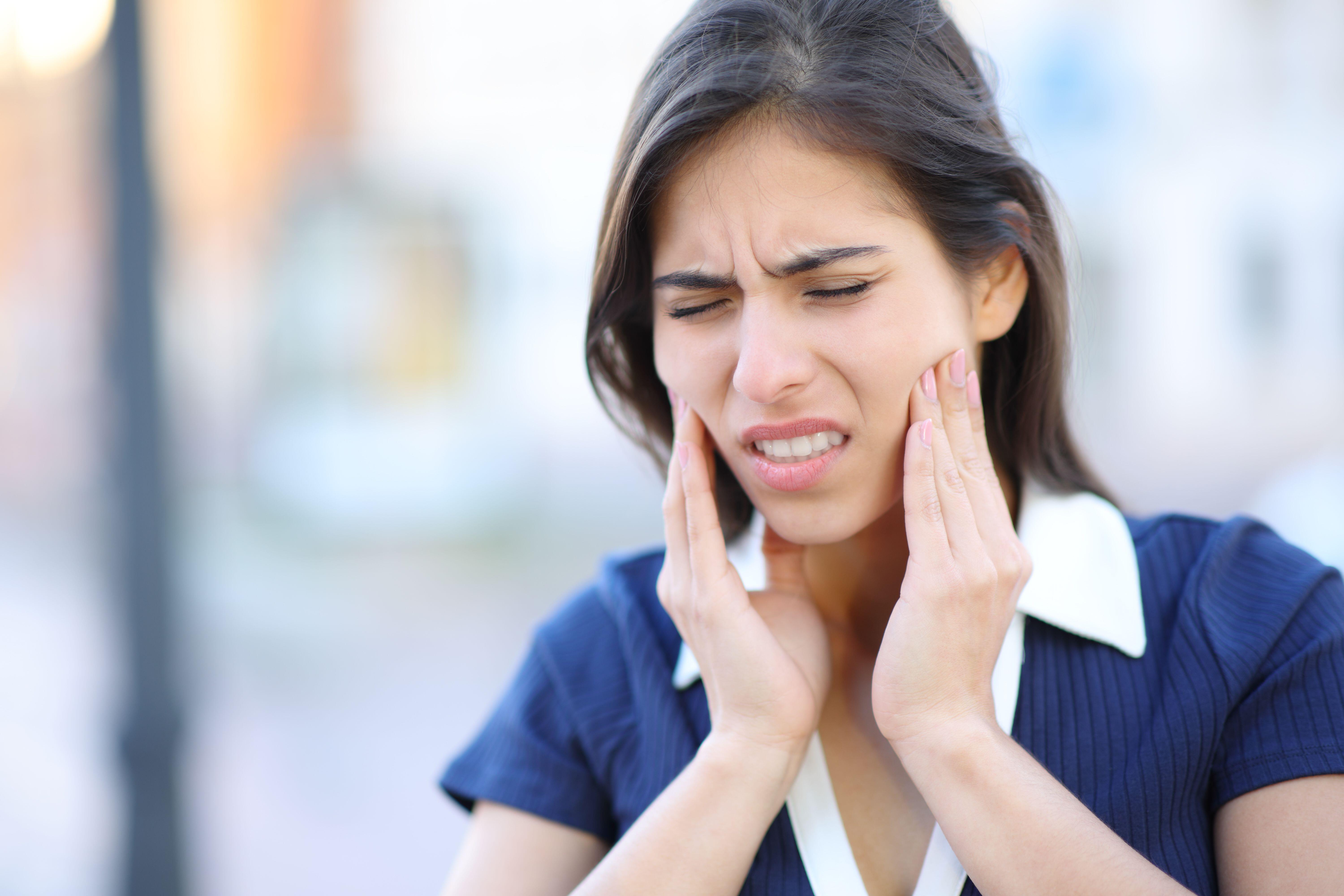 Young woman walking in a street suffering from jaw pains