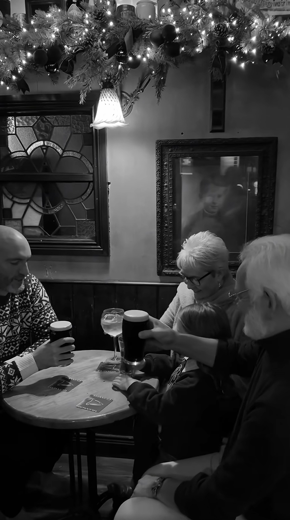 Black and white image of a family of four enjoying a pint at the pub