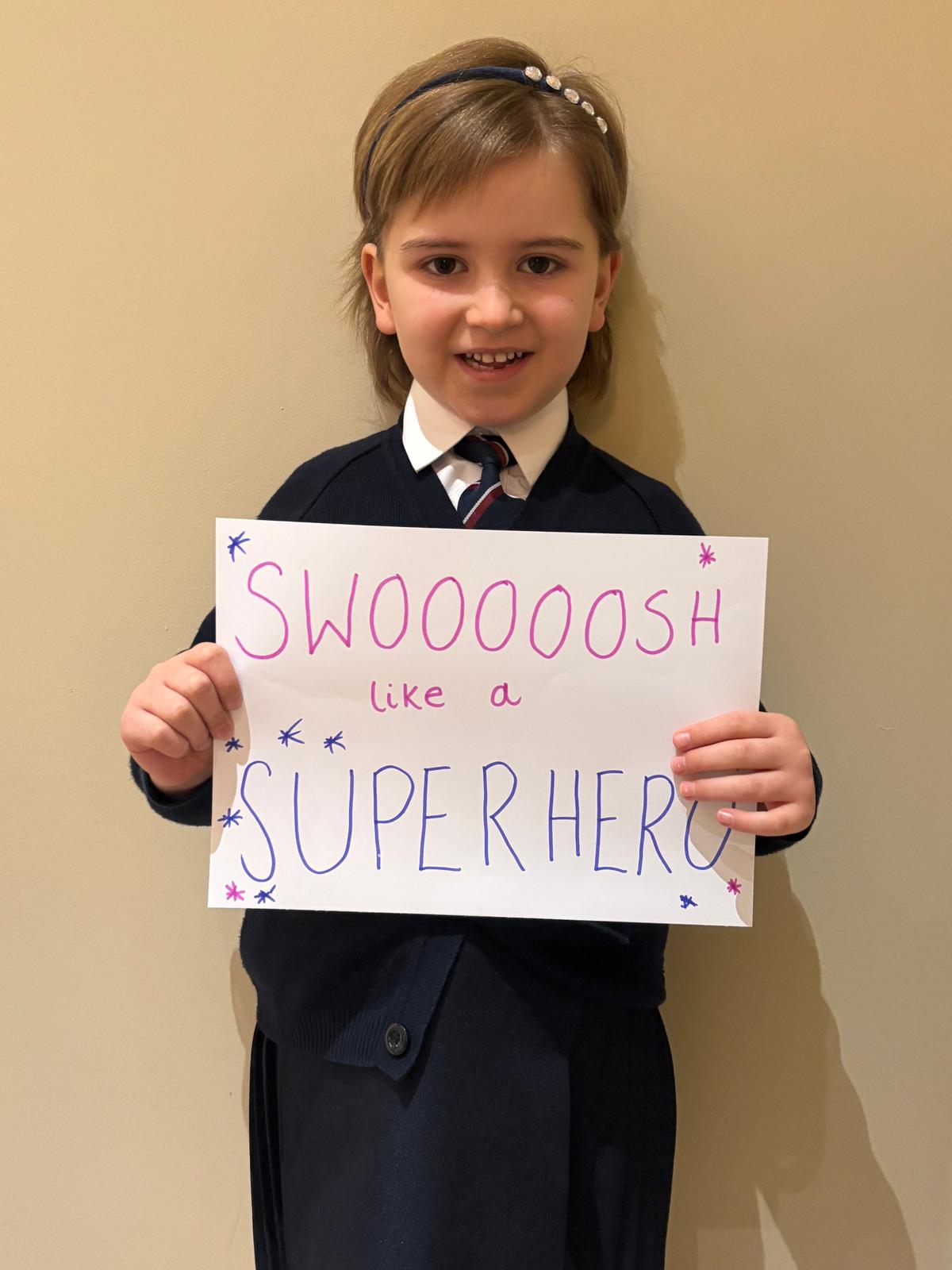 Fearne Stewart holding up a sign with the words 'Swooooosh like a superhero'