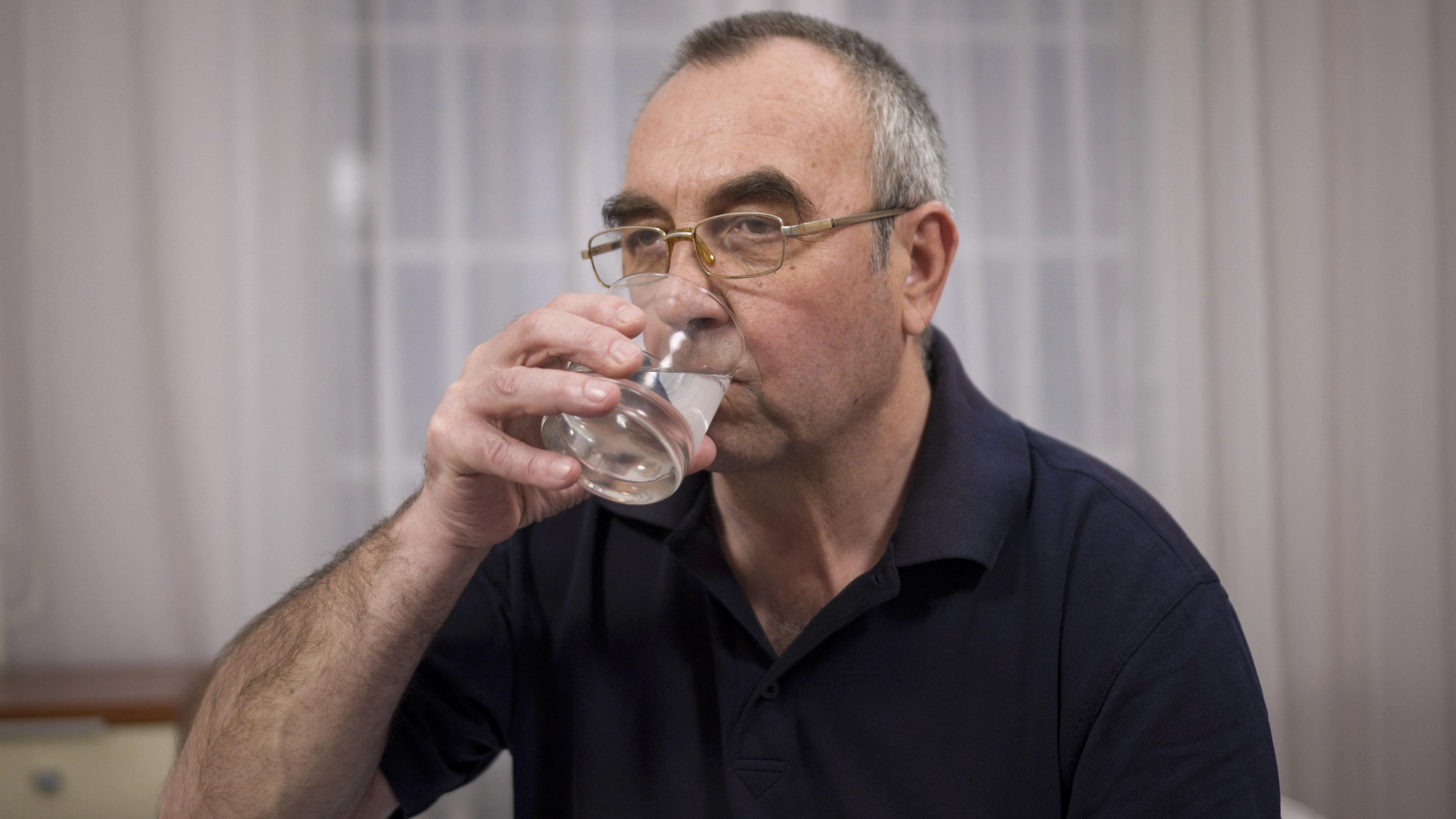 Elderly man drinking a glass of water