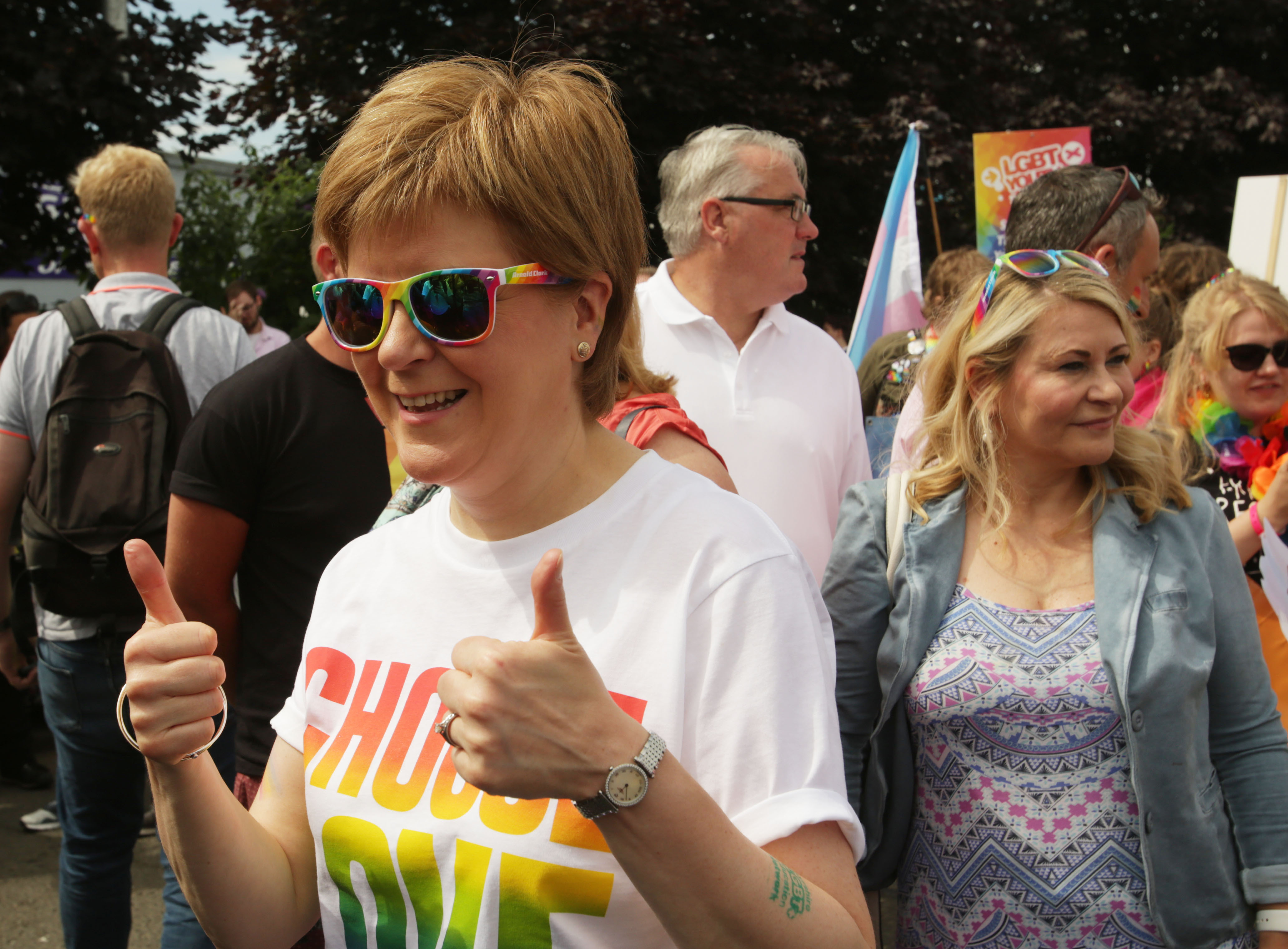 Nicola Sturgeon smiling and giving the thumbs up, while wear rainbow sunglasses and a T-shirt reading 'Choose love'