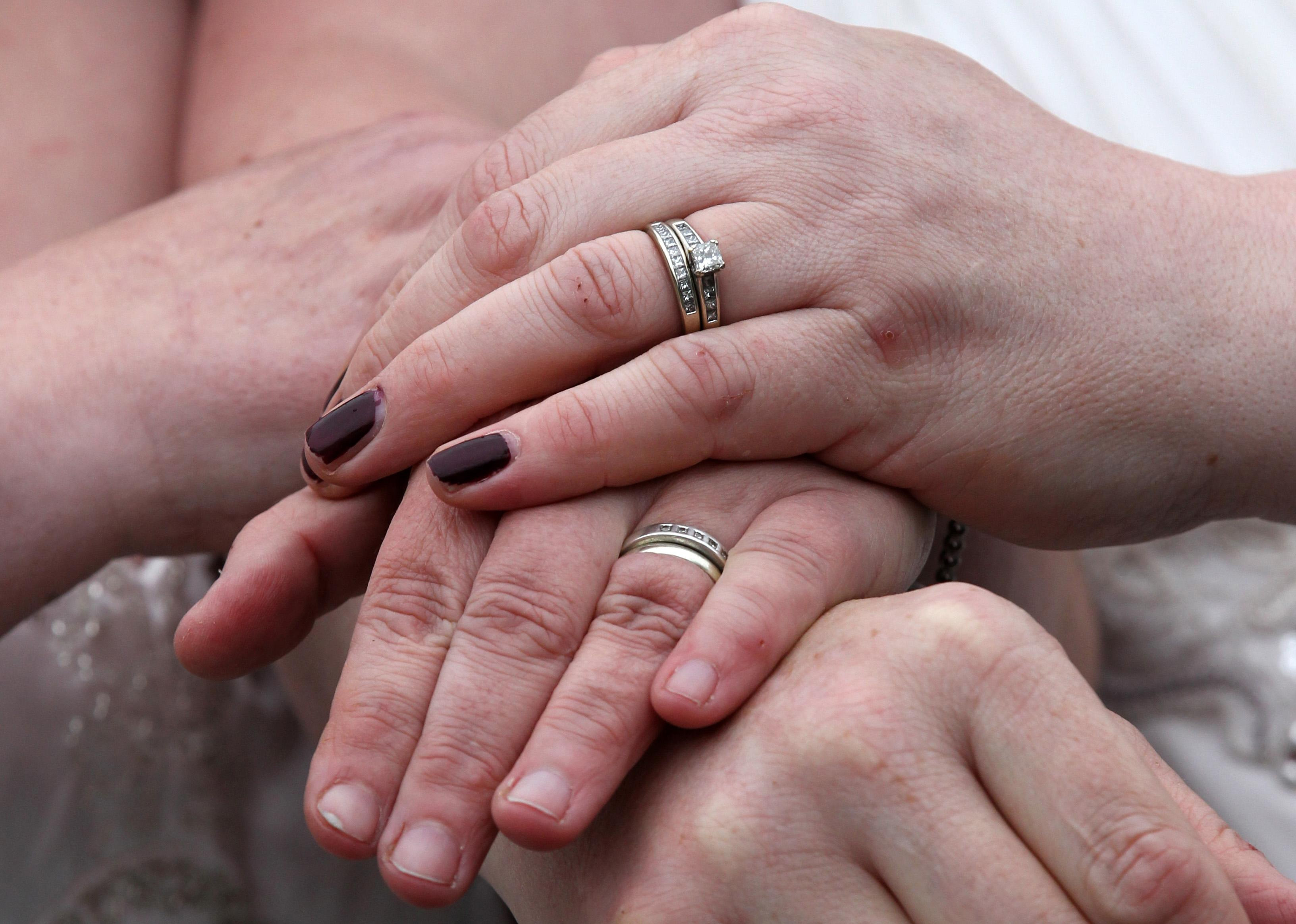 Two pairs of hands showing their wedding rings