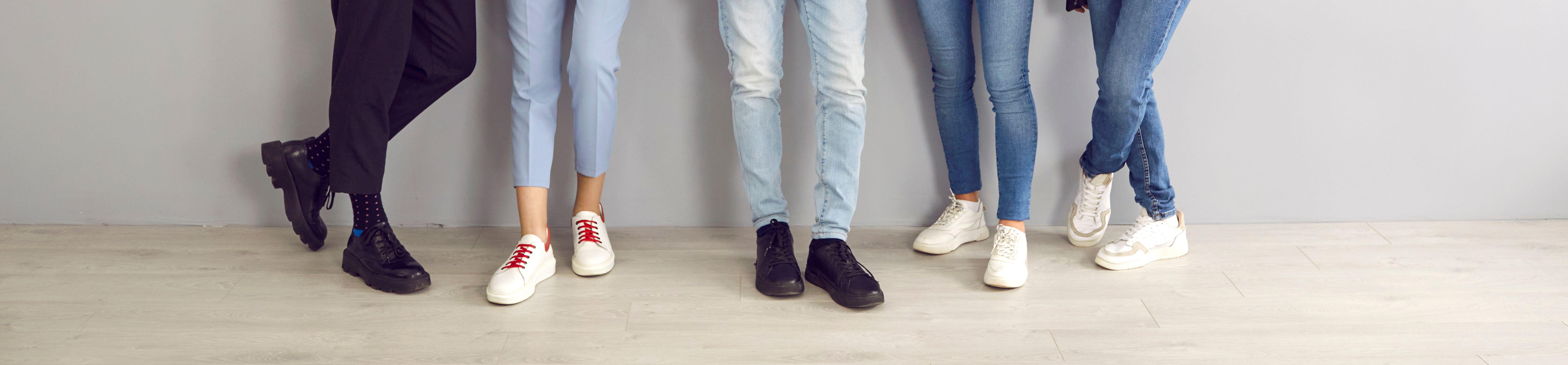 Group of young people in jeans, pants, trainers and classic shoes standing in a studio