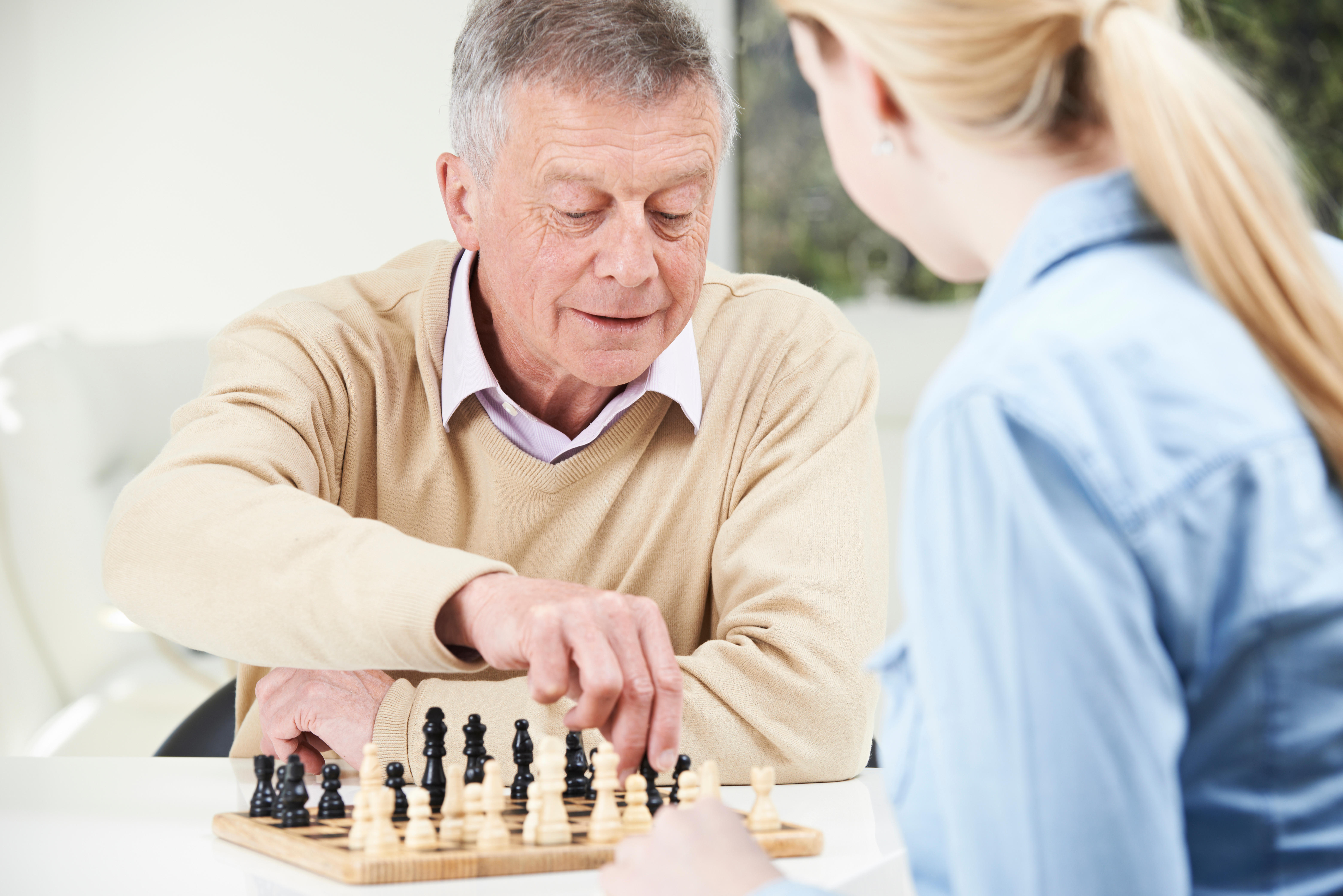 Senior Man Playing Chess With Teenage Granddaughter