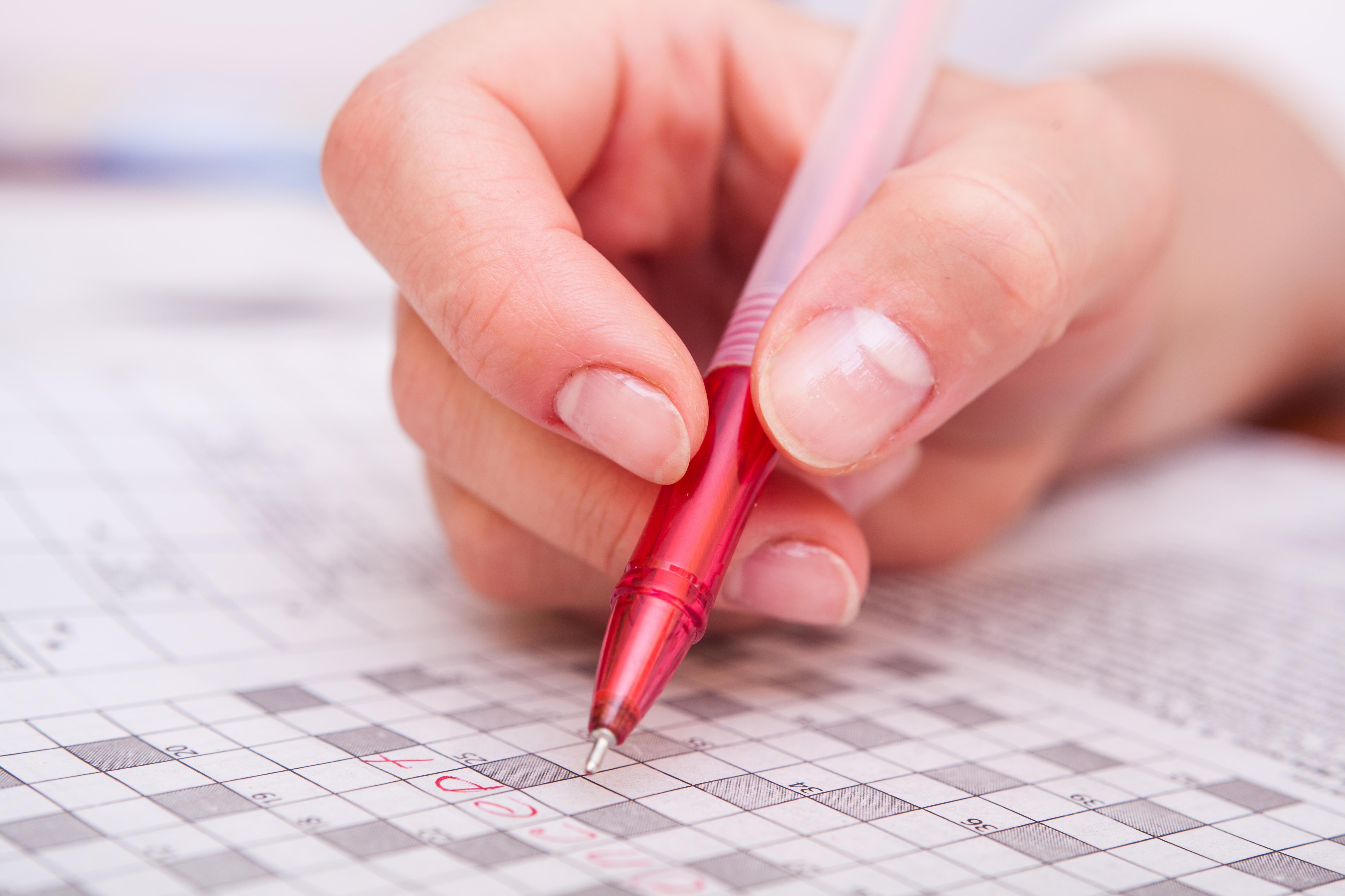 Close-up picture of female hand doing crossword 