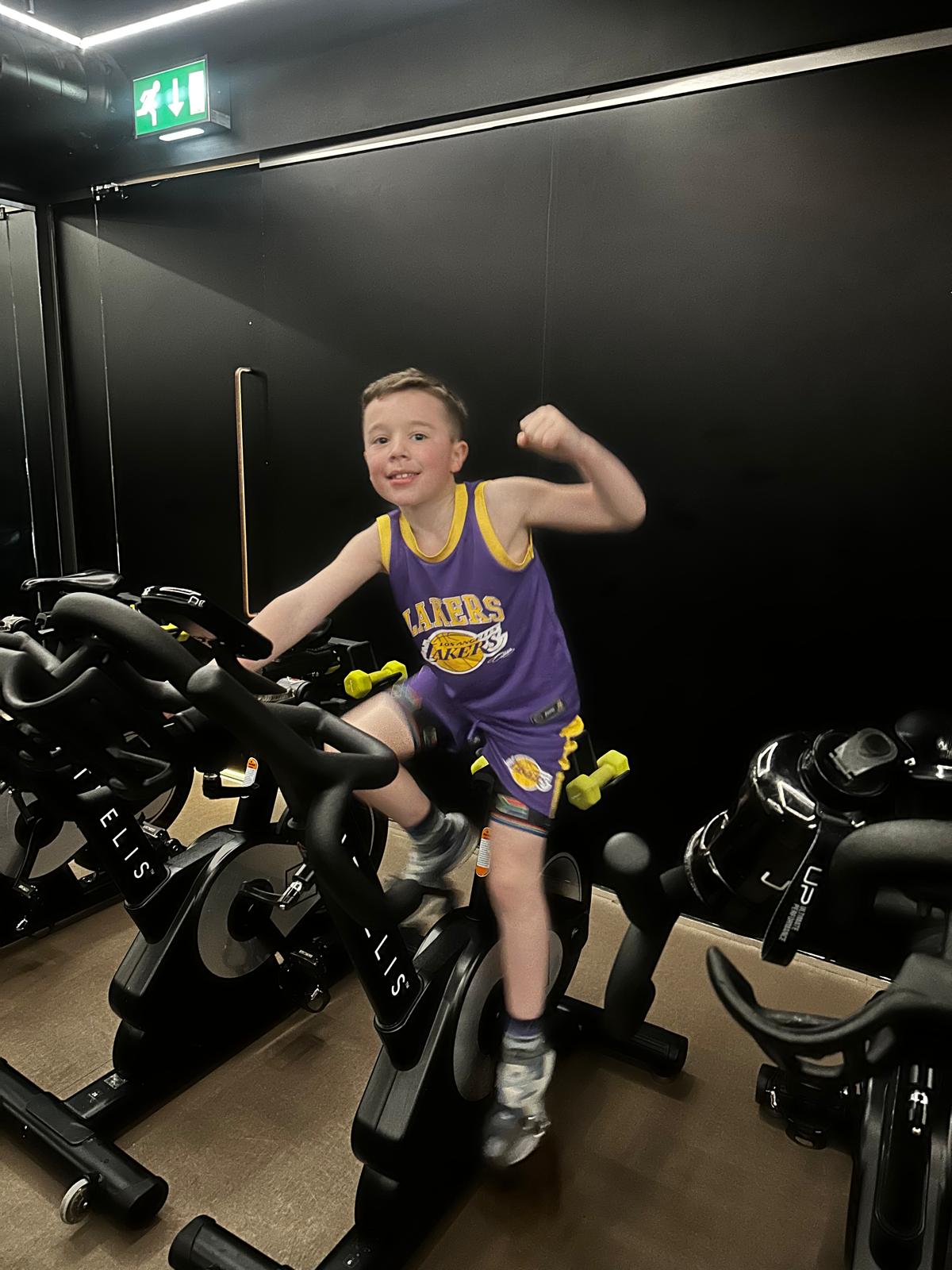 Harvey Goodman training on a stationary bike, holding a fist up in the air