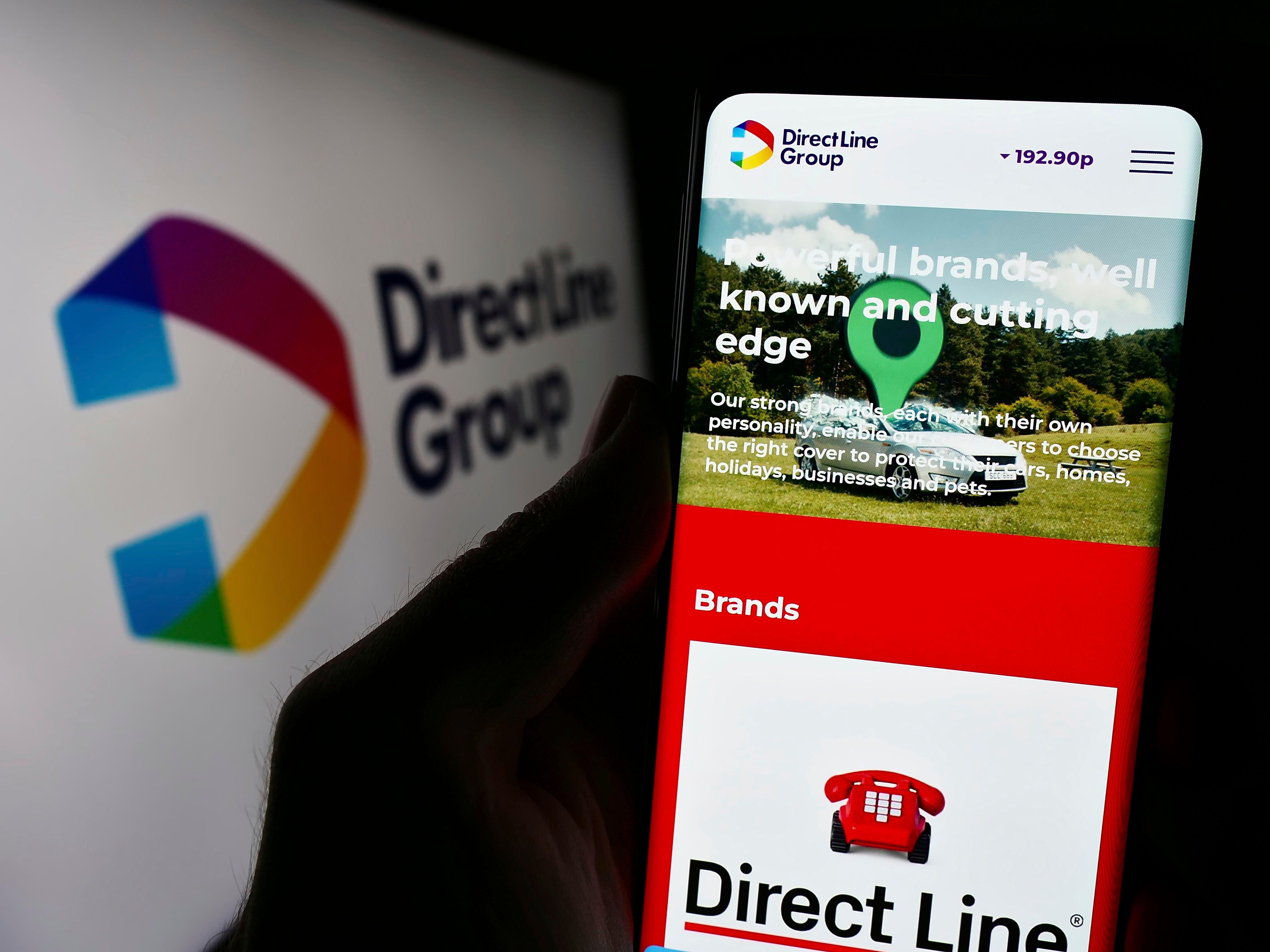 A person holding a smartphone with the Direct Line Insurance Group web page displayed