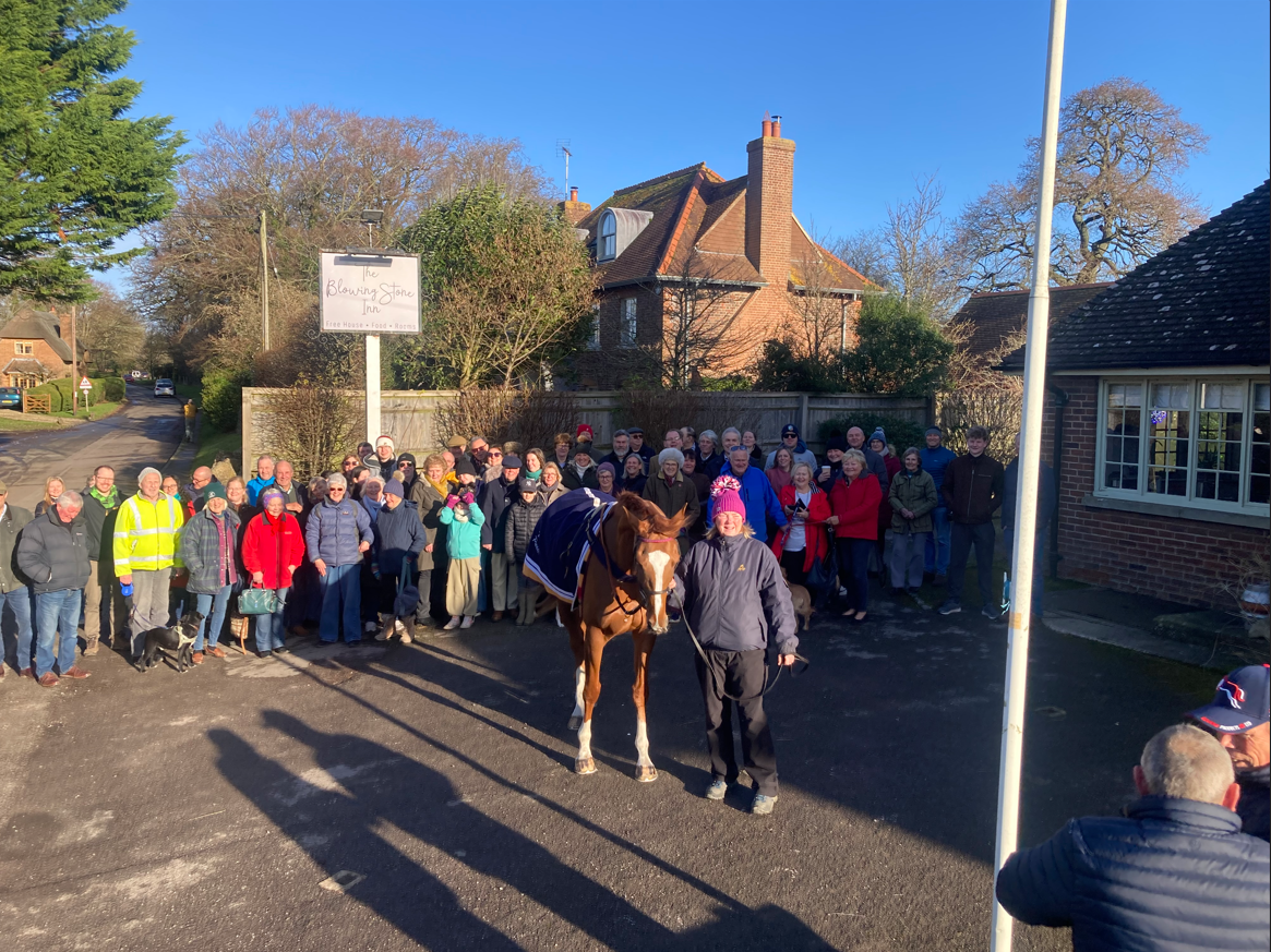 Crowd of people with racehorse outside a pub