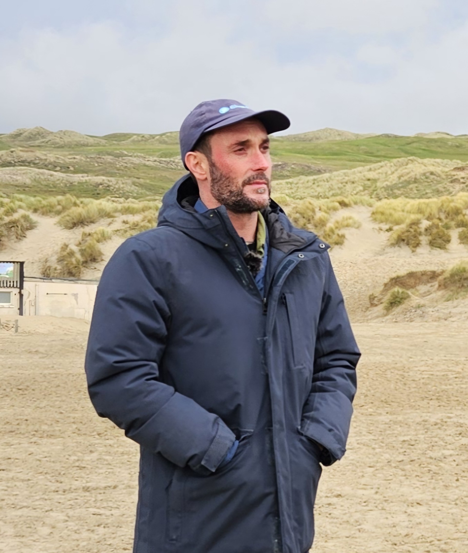 Daniel Poole on a beach in a coat and cap