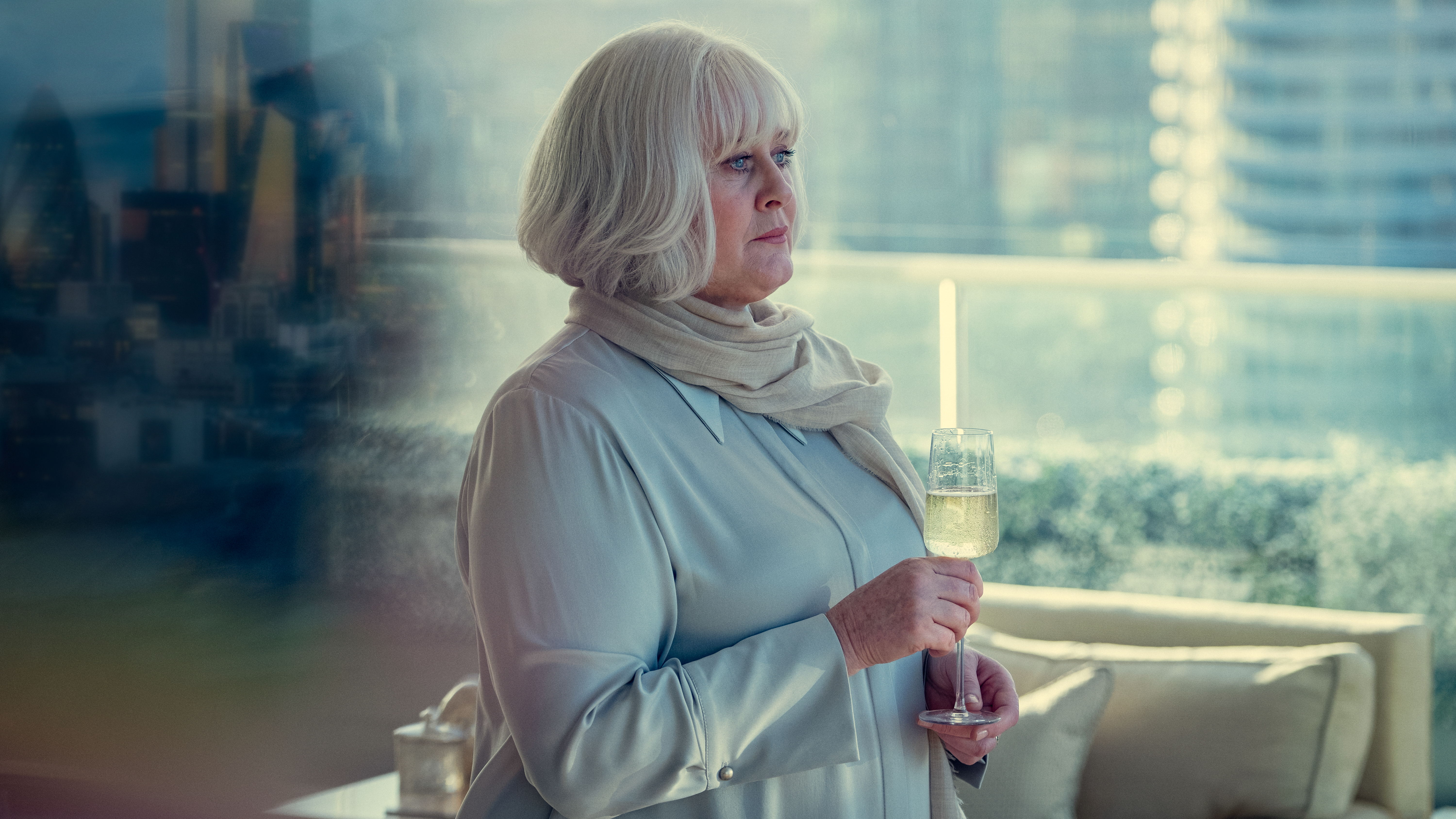 Sarah Lancashire in character, holding a glass of Champagne