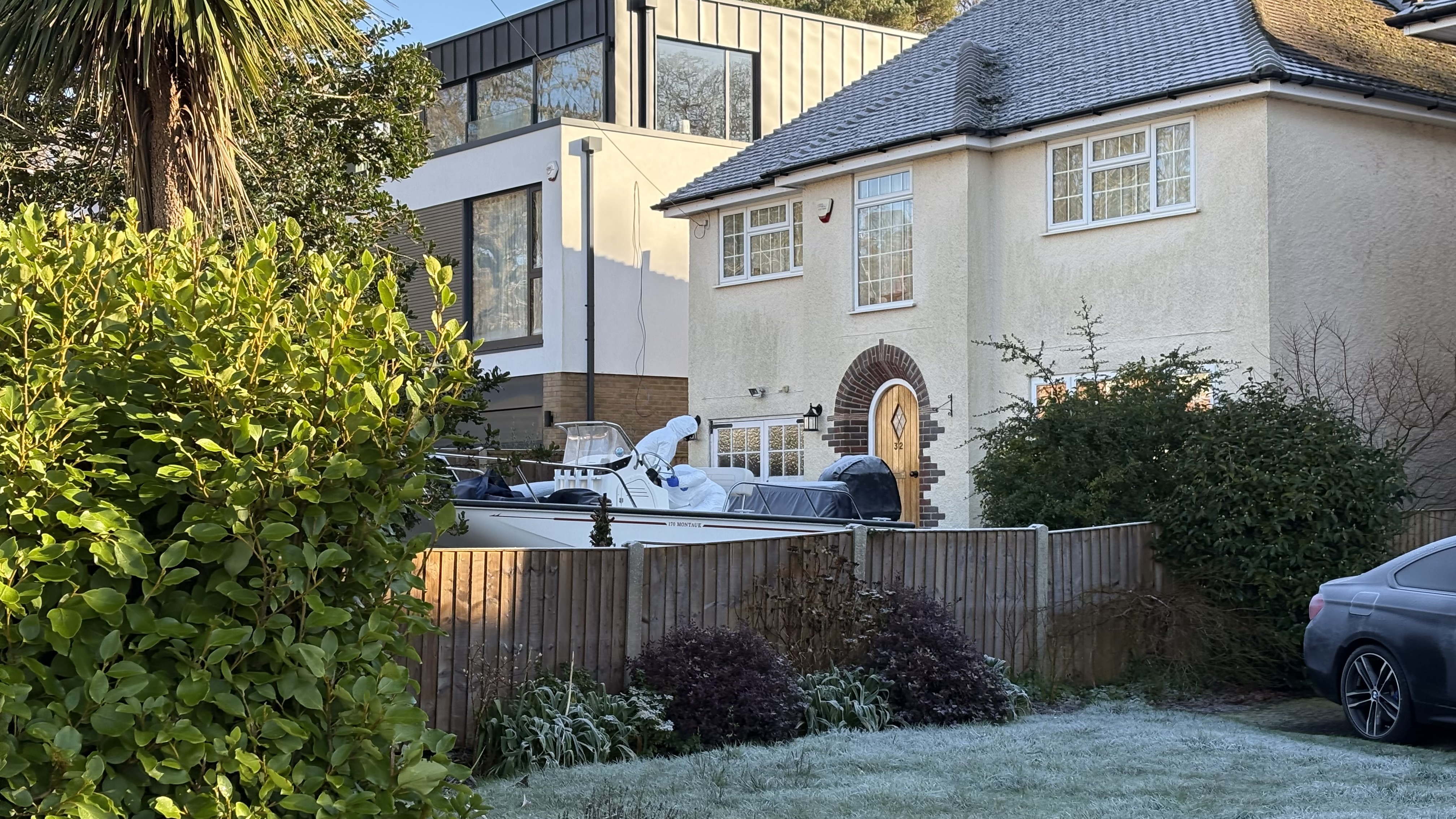 Forensic officers carry out searches of a boat and car on the driveway of a house in Poole