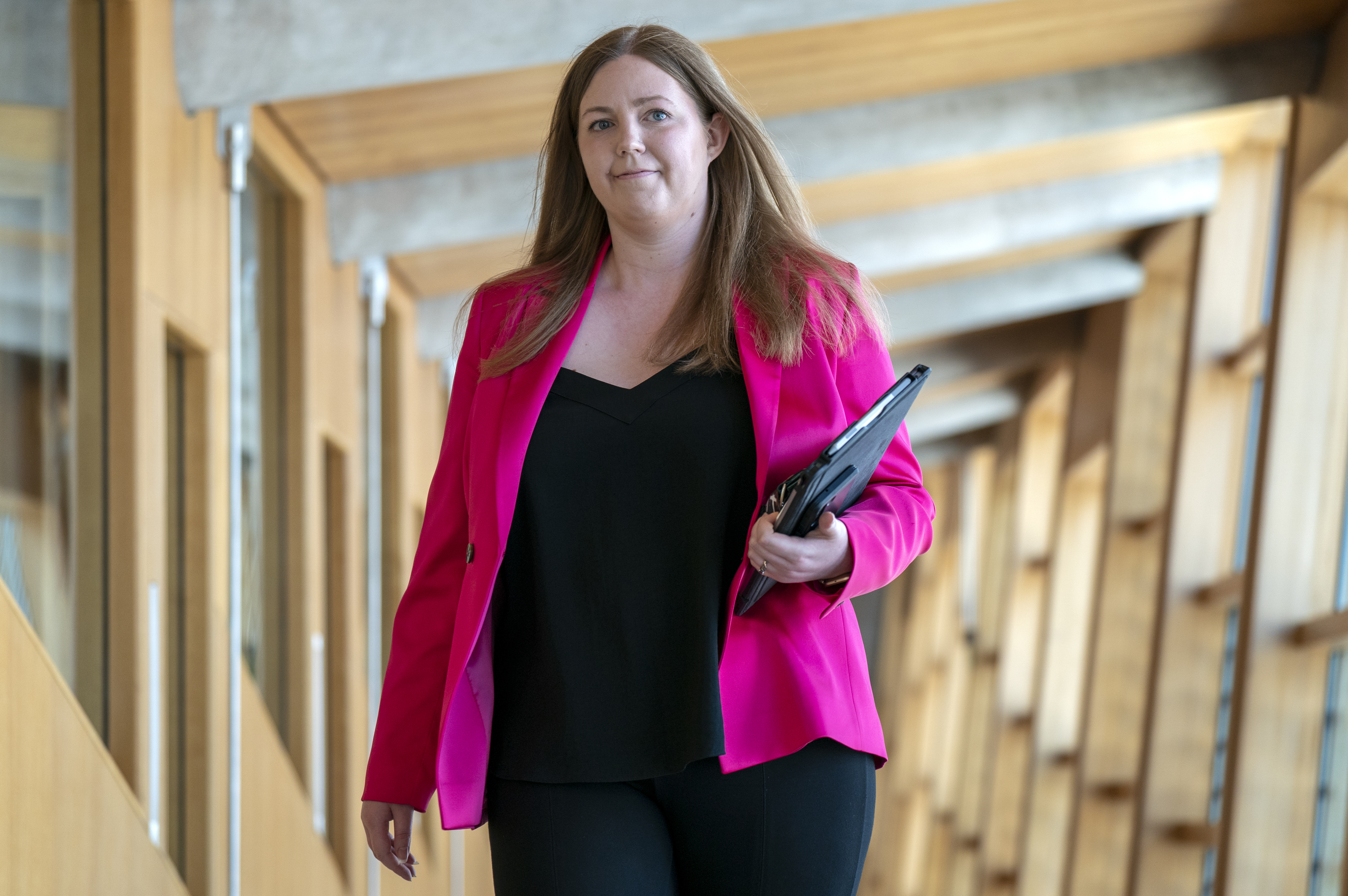 Gillian Mackay smiling while walking through a corridor at Holyrood