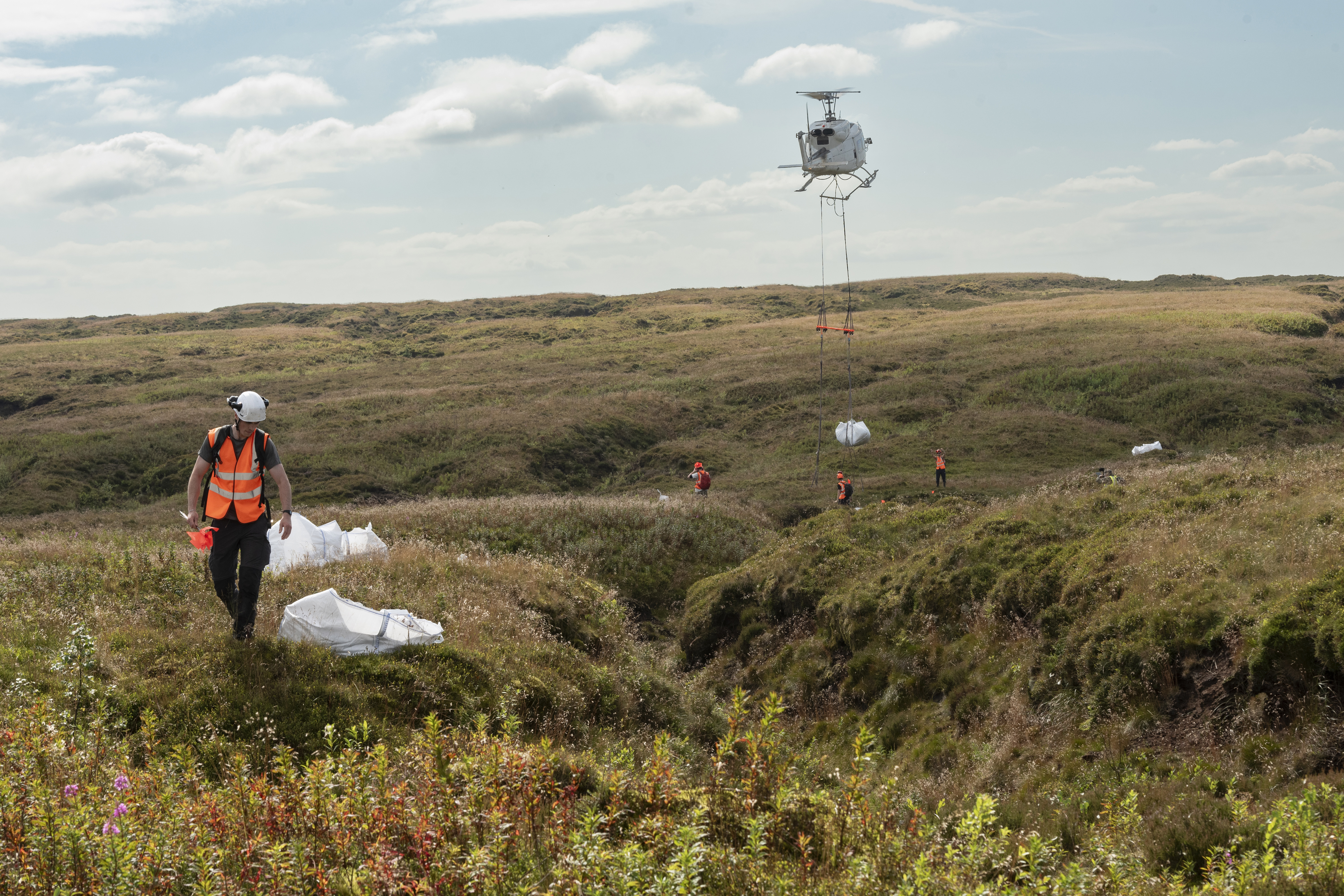 A helicopter and teams in hi-vis jackets as part of peatland restoration project