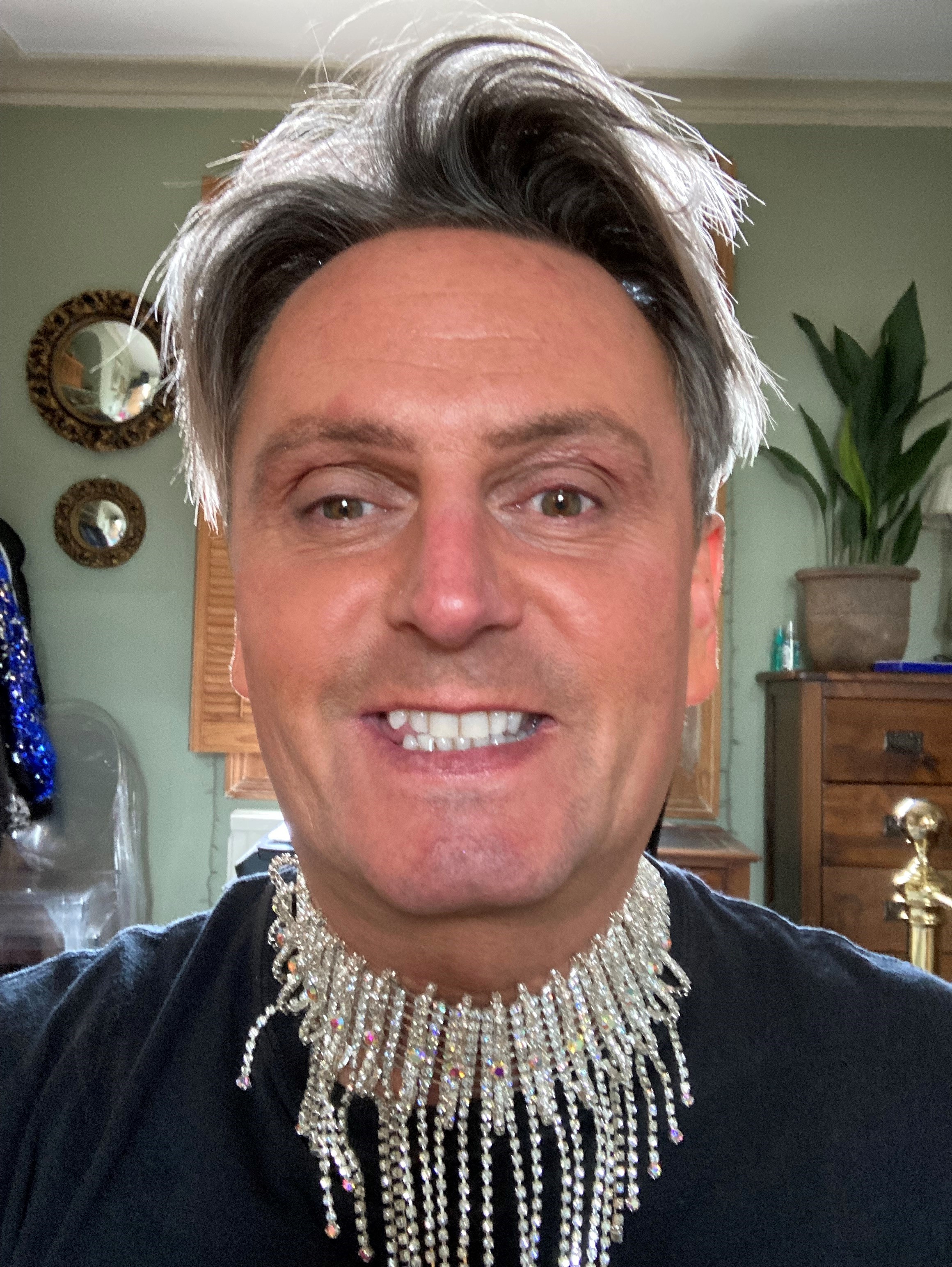 Selfie of a man with grey hair wearing an elaborate, shiny jewellery around his neck