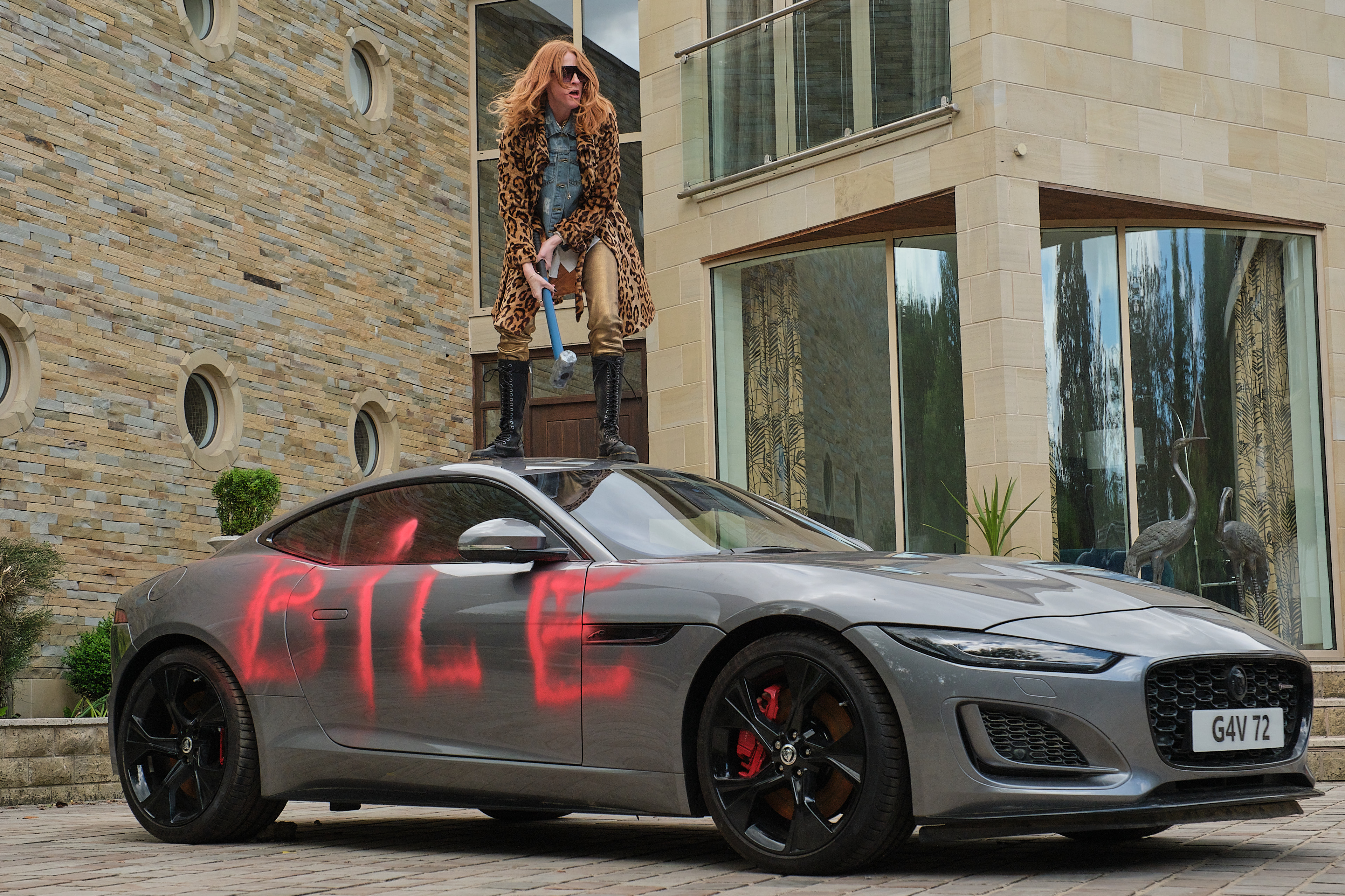 Rosalie Craig as Kitty standing on a spray-painted car