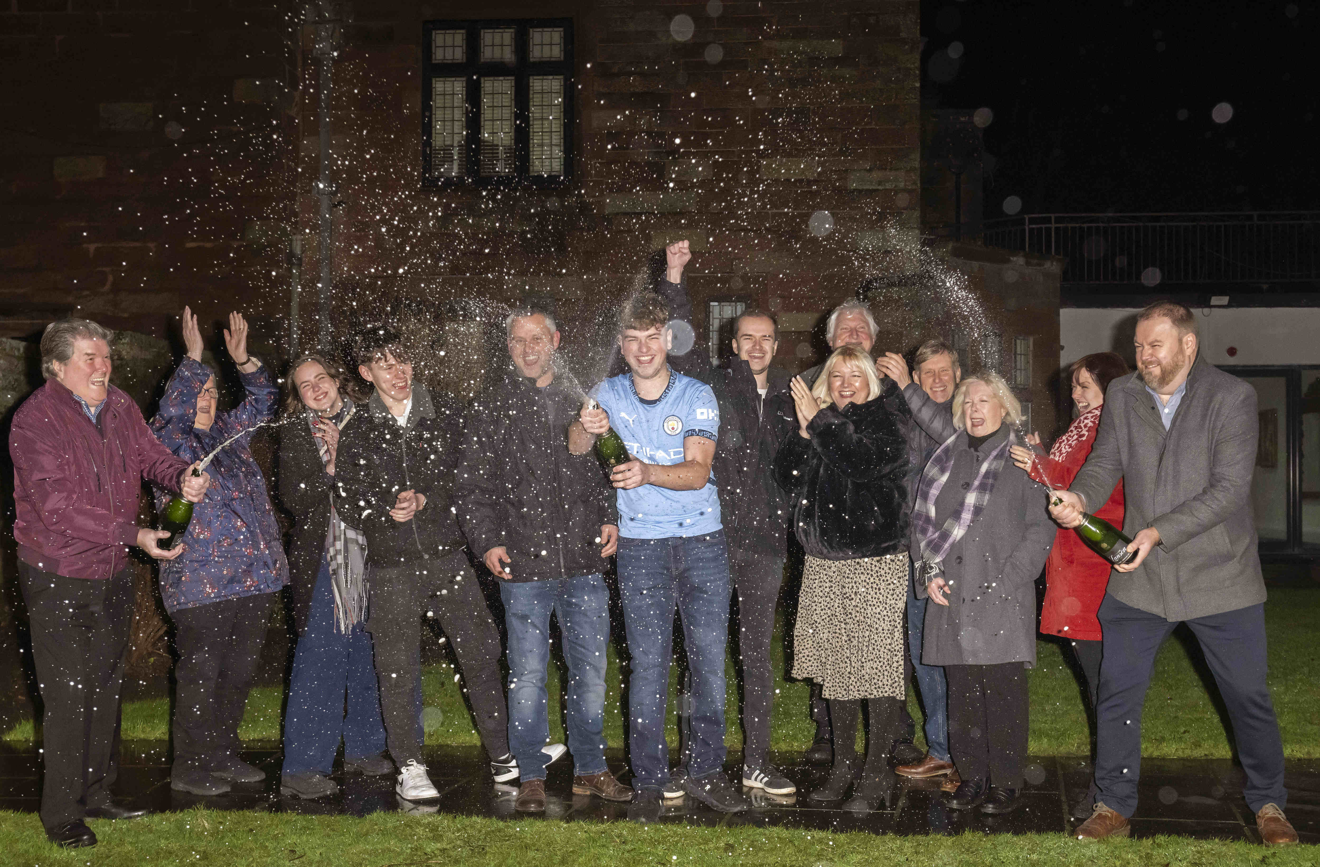 Lottery winner James Clarkson with champagne bottle to celebrate win with extended family