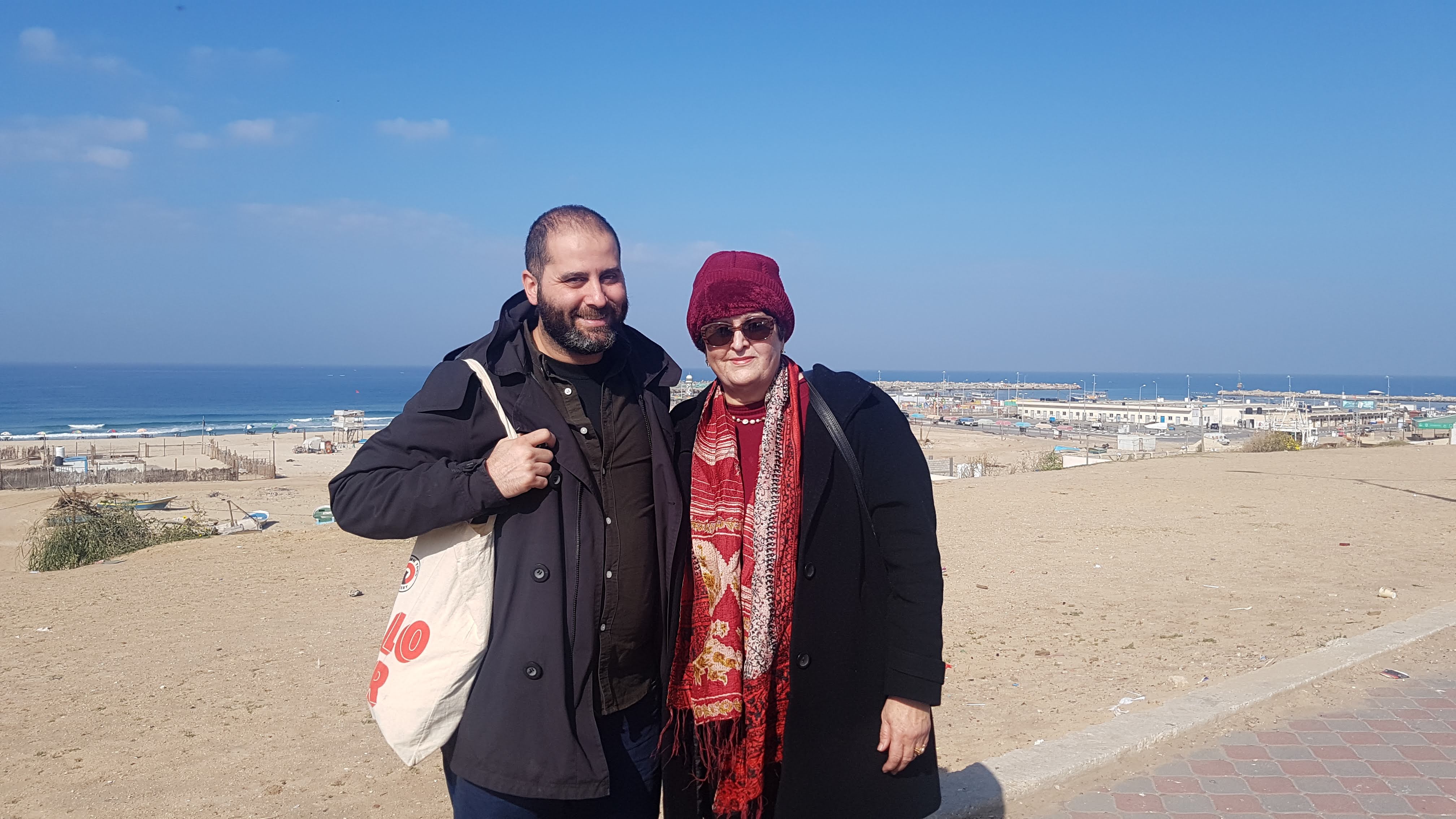 A man and a woman smiling in front of a beach