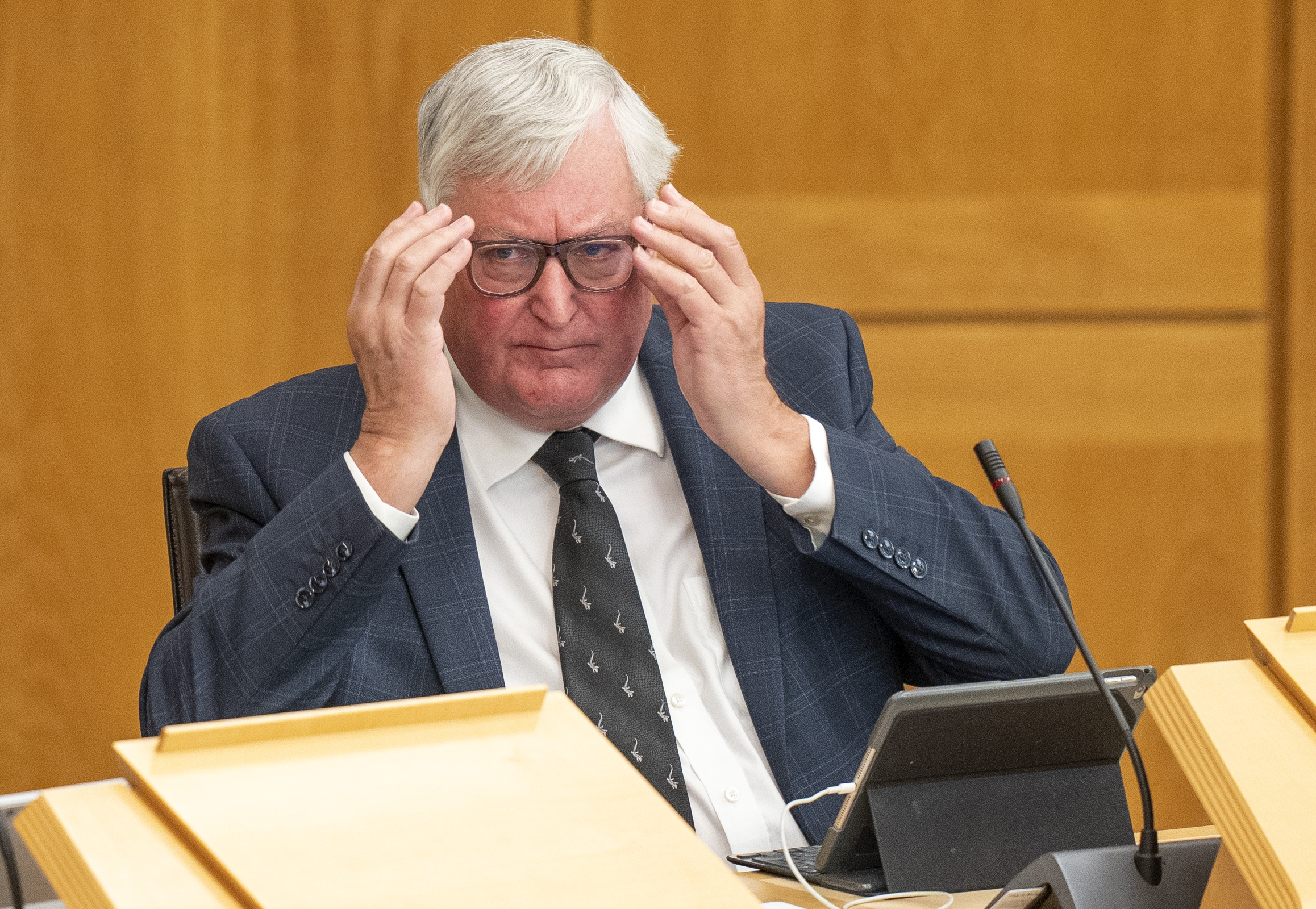 Fergus Ewing adjusts his glasses during a debate in the Scottish Parliament