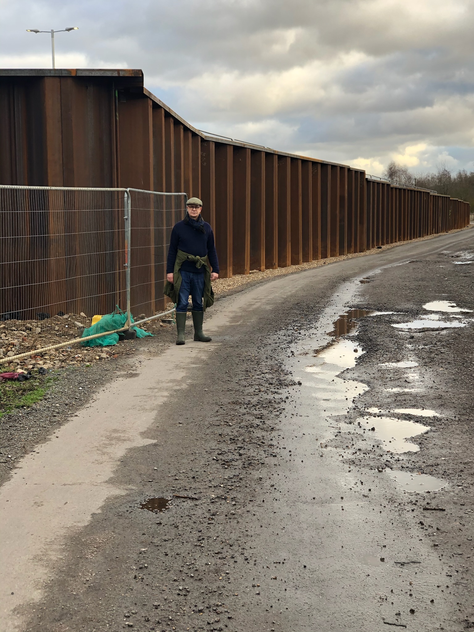 A person stands next to the steel retaining wall of the carpark