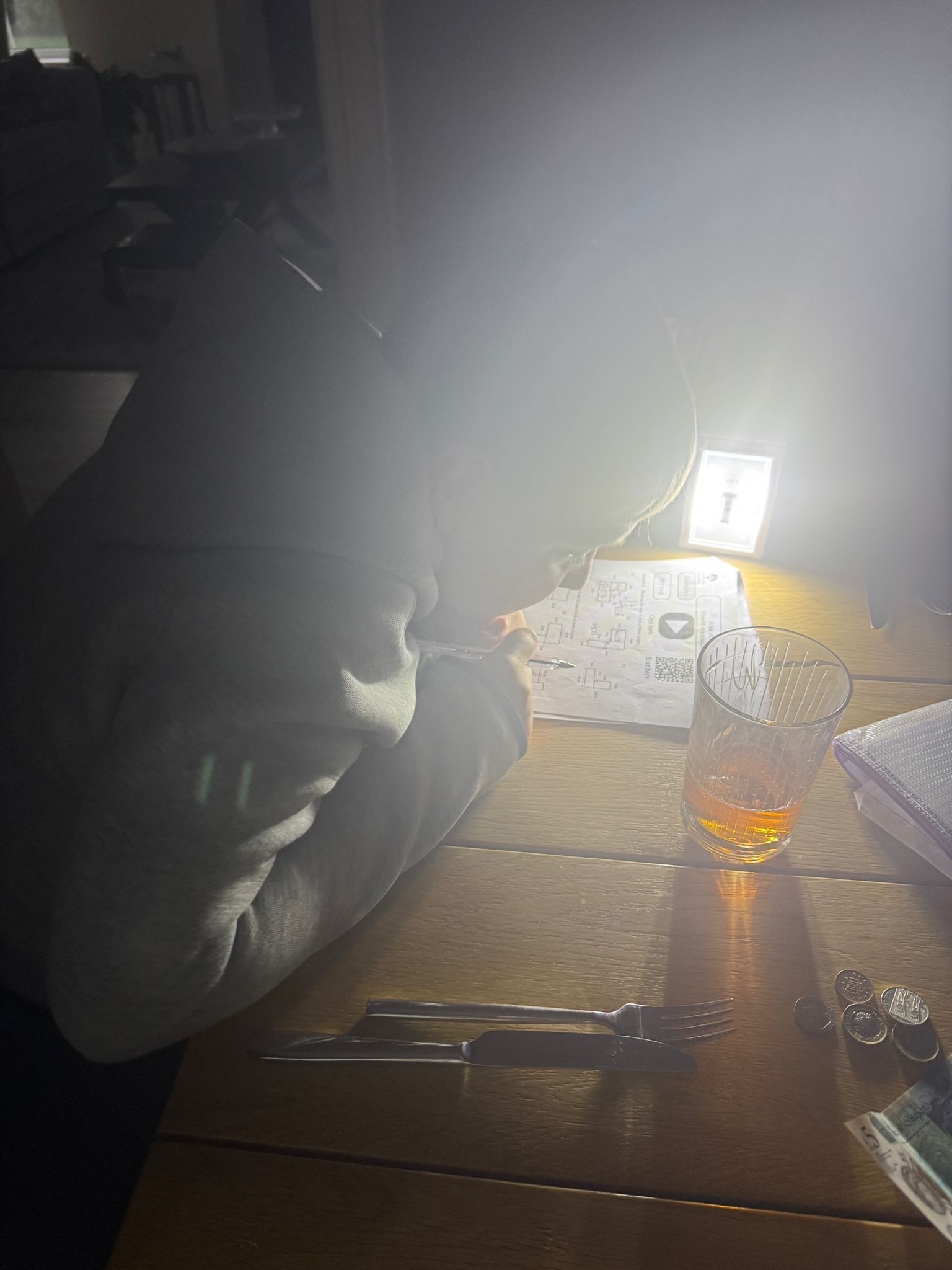 Young boy doing homework at a table with a torch during a power cut in his home