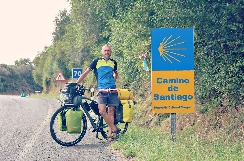 Volodymyr Muliar posing with his bike near a sign