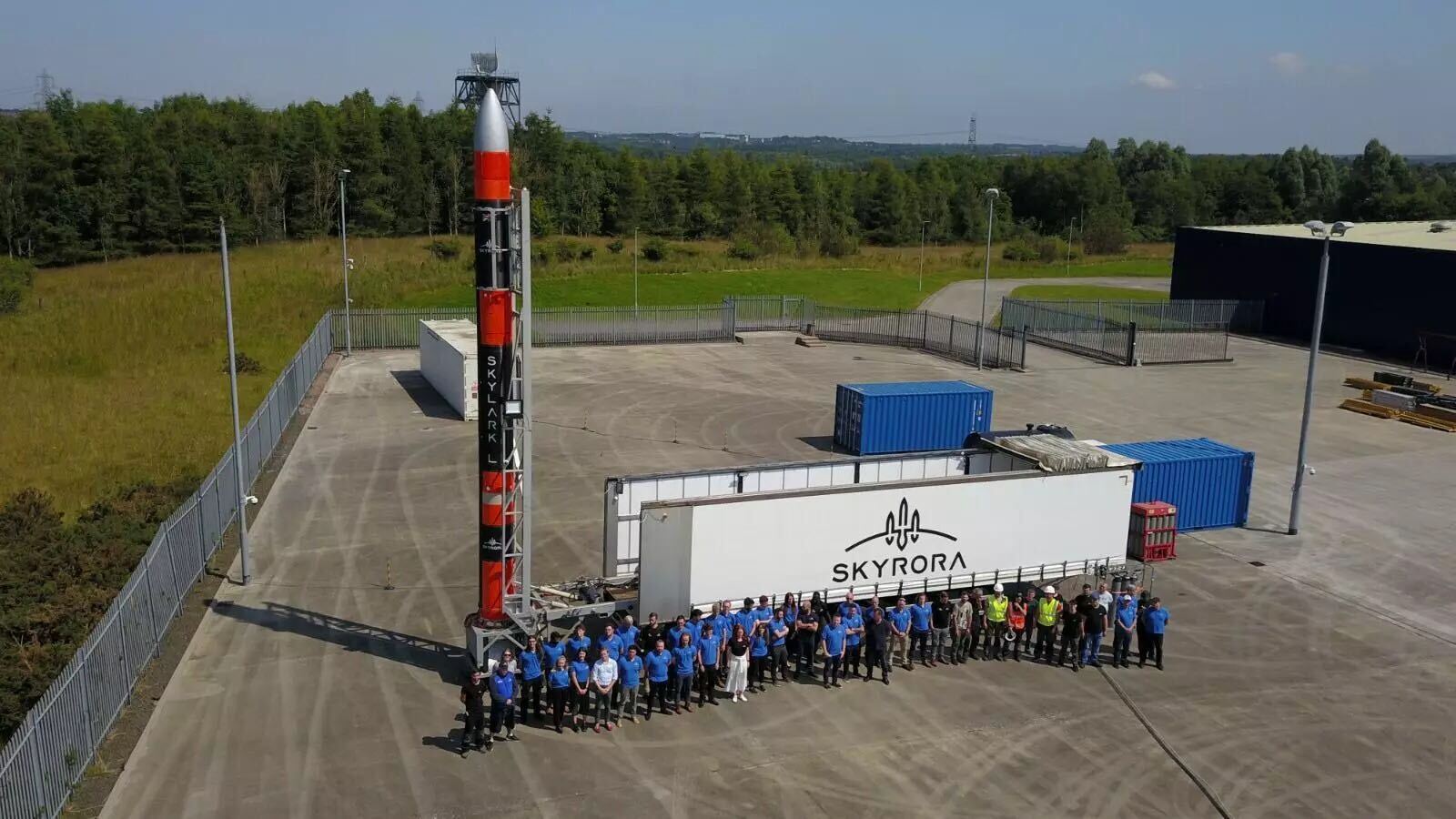 A Skyrora rocket with a large group of staff standing alongside it, looking up to the camera