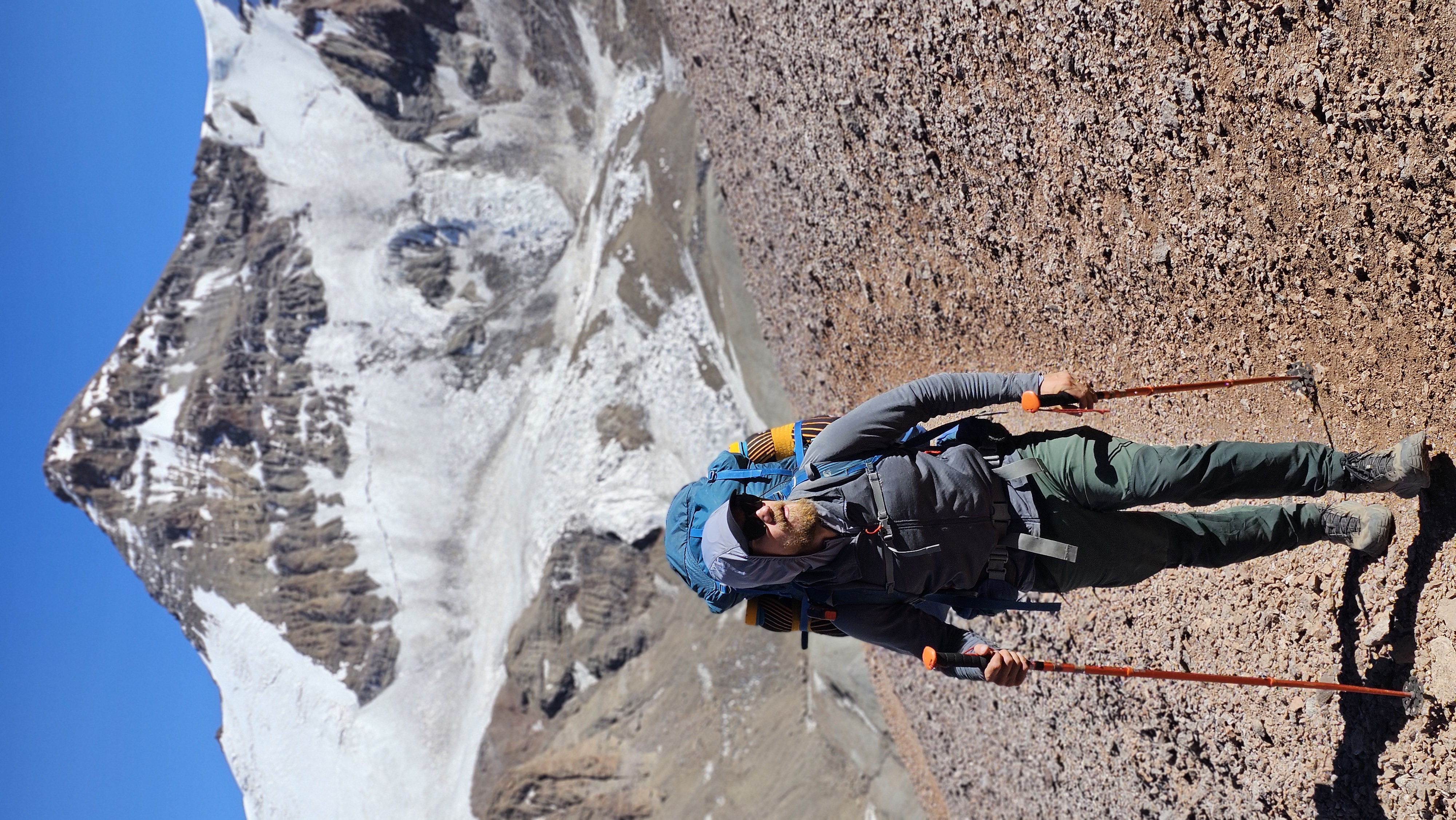 Man wearing a large rucksack and using hiking sticks at Aconcagua, the highest mountain in South America