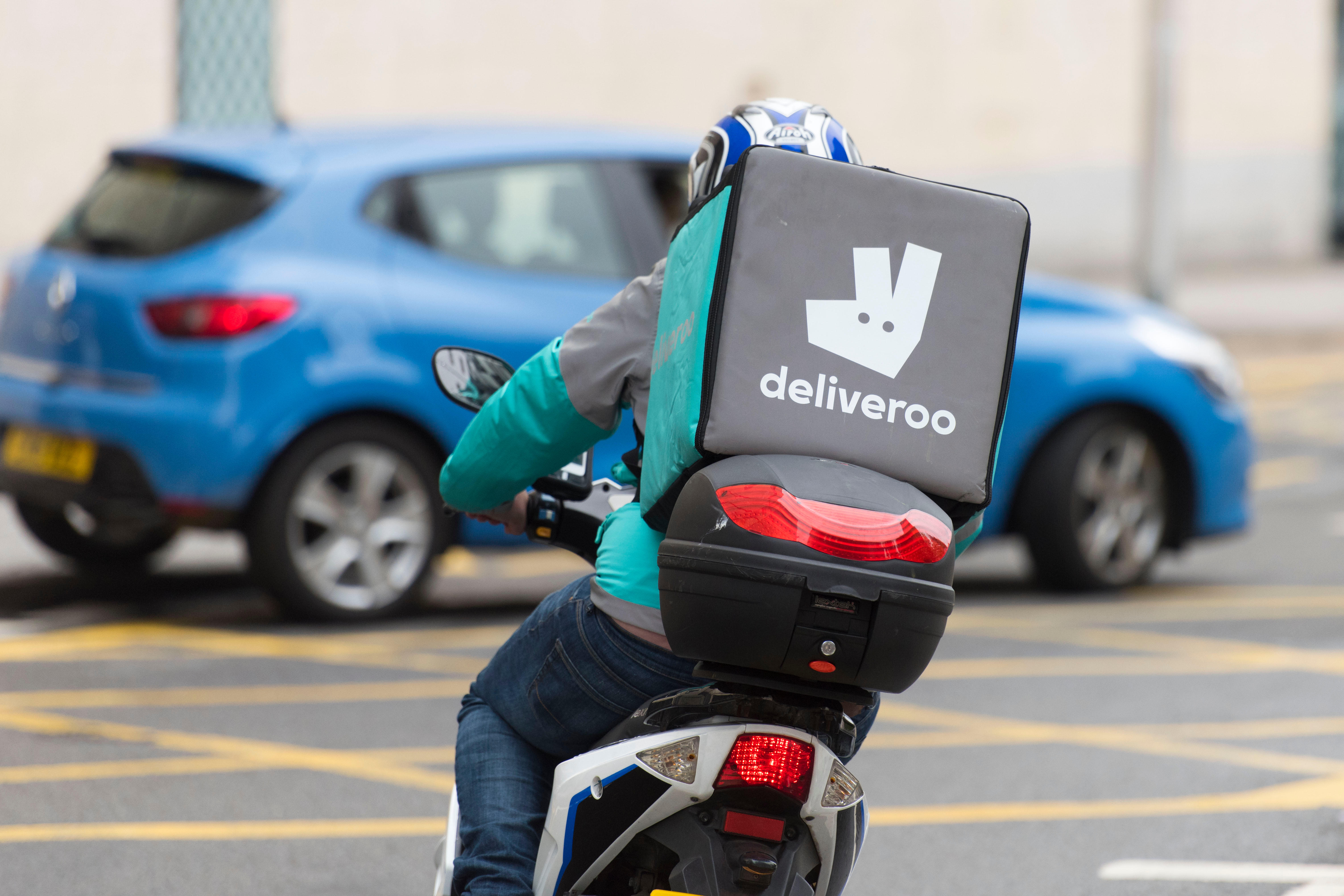 A Deliveroo rider on a moped making a food delivery