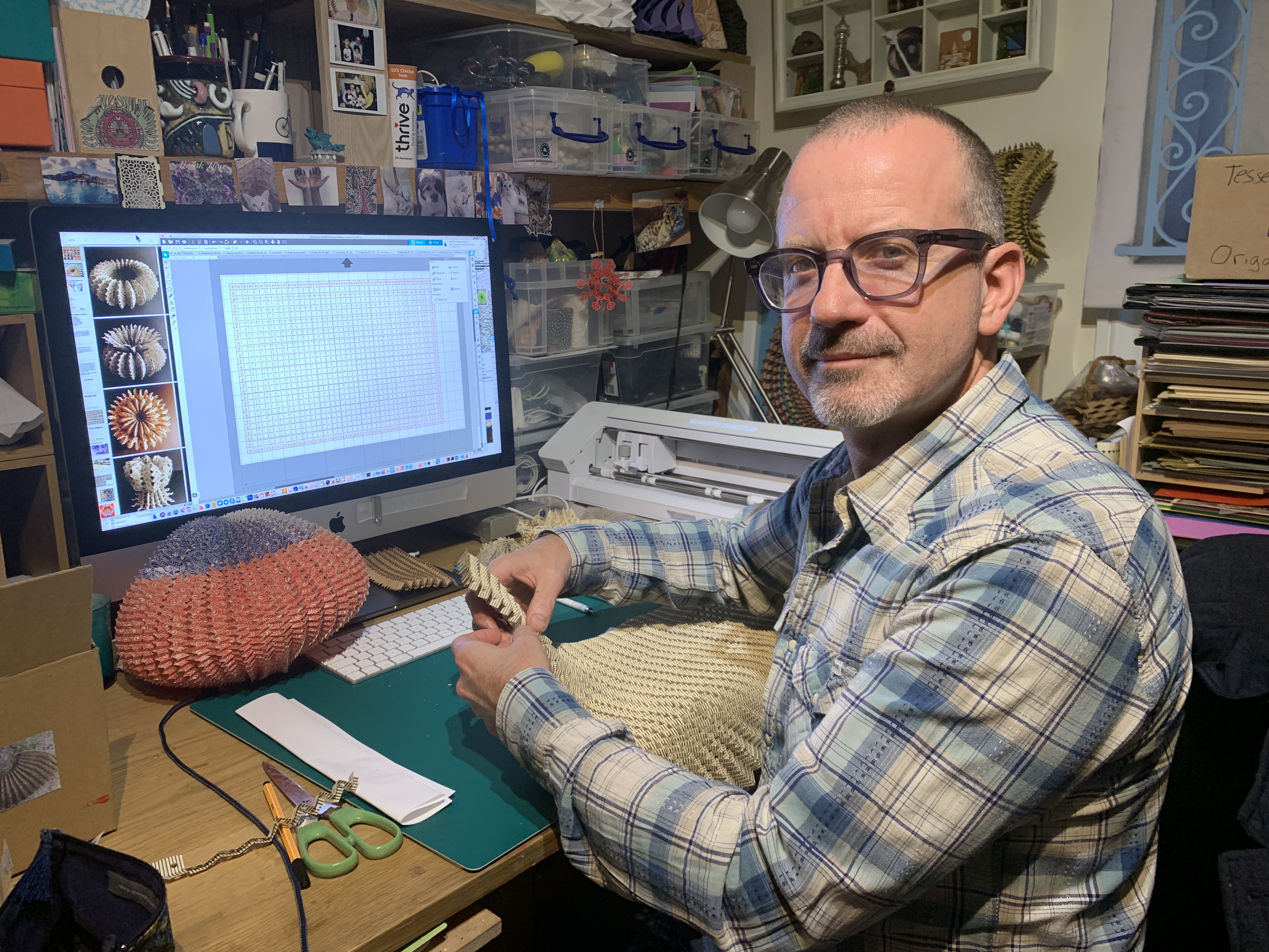 A man sits at his desk with his computer in the background