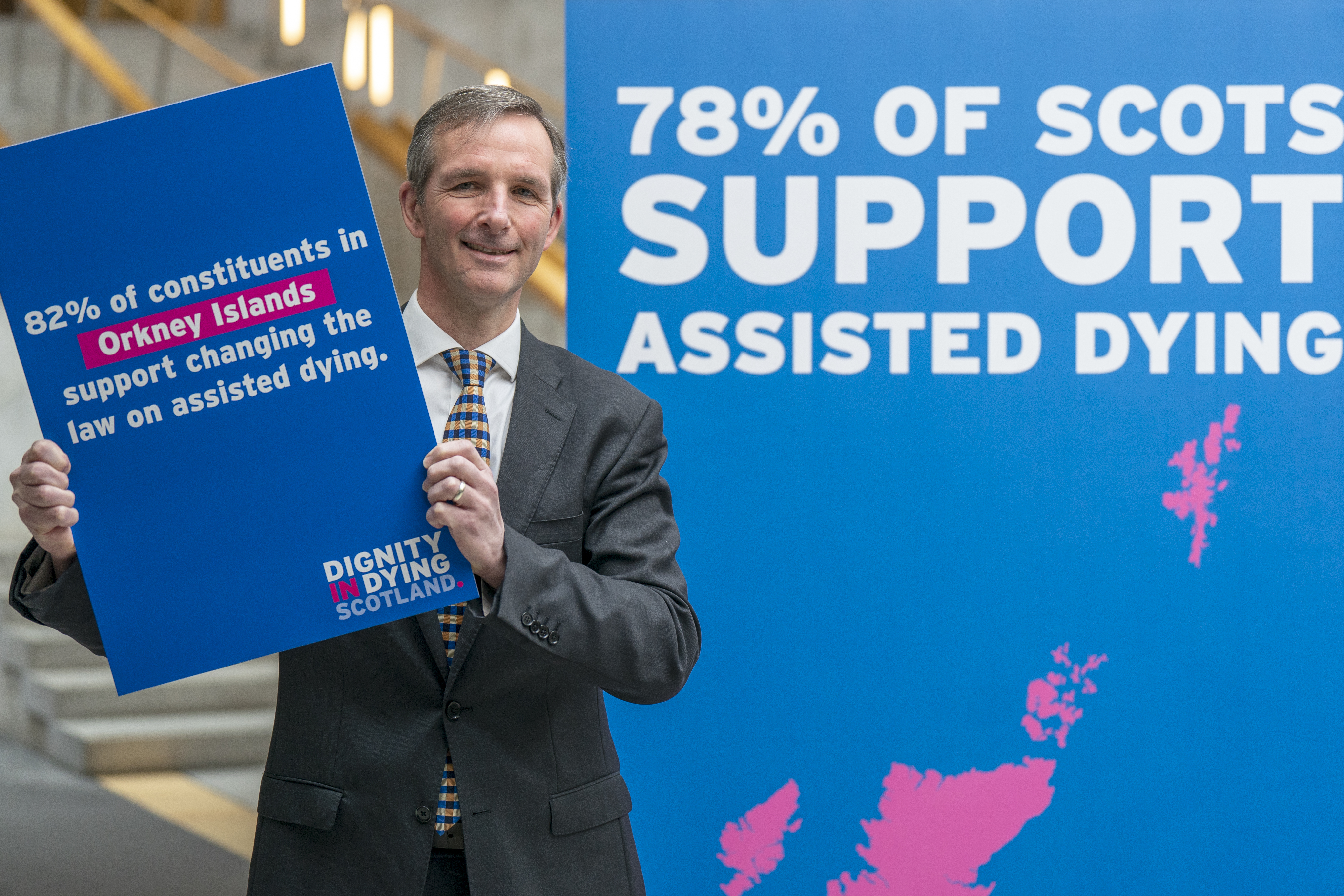 Liam McArthur holding placard detailing support for assisted dying