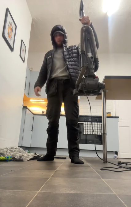 Screenshot from a TikTok video of a young man holding a vacuum cleaner