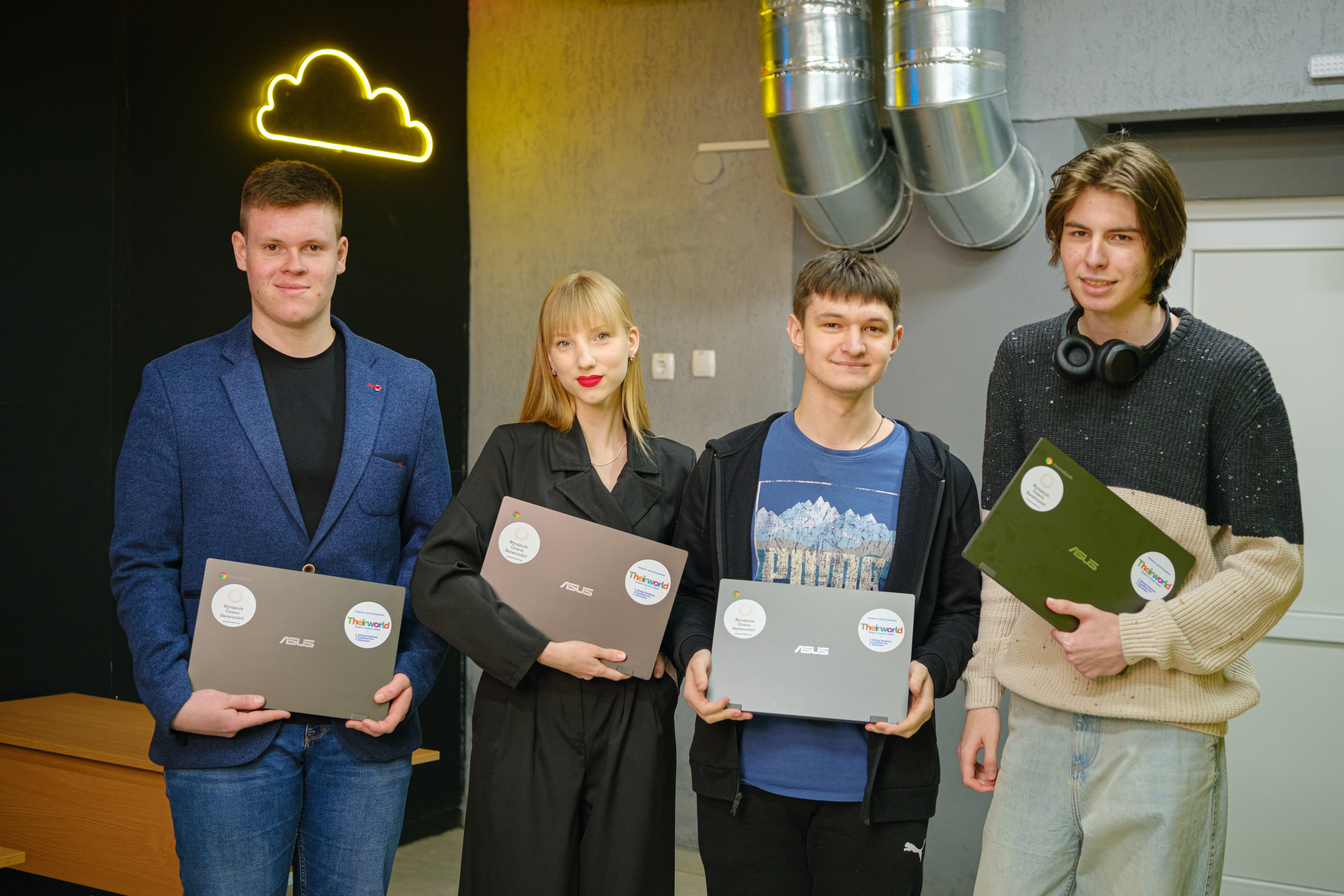 Four teenagers smiling while holding laptops