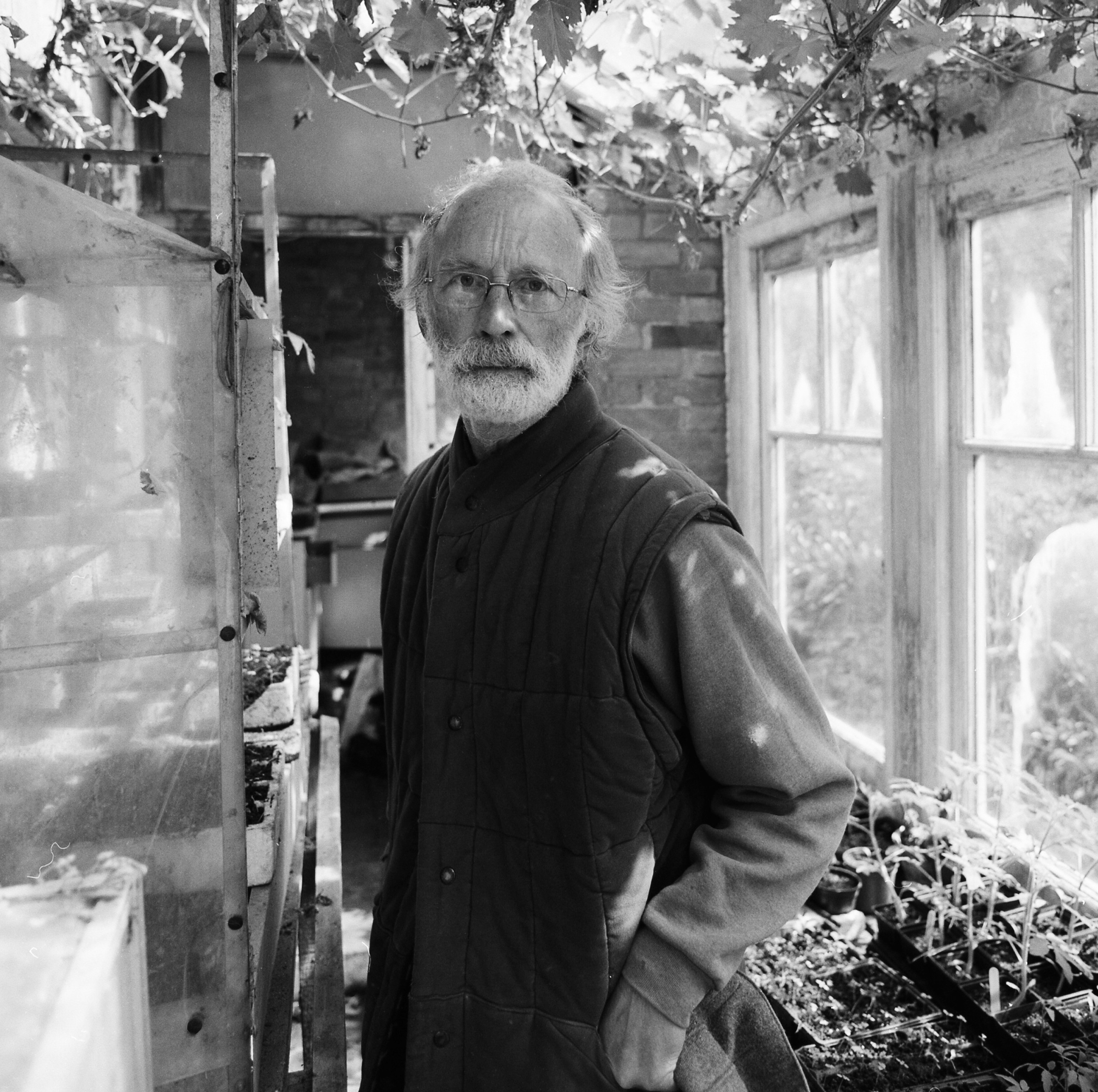 Black and white photo of Hugo Morley-Fletcher in a green house